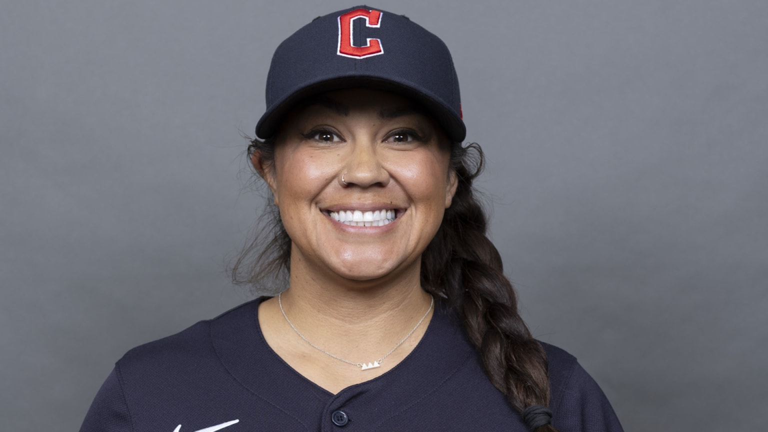 A woman smiling wearing a cap with a C on it