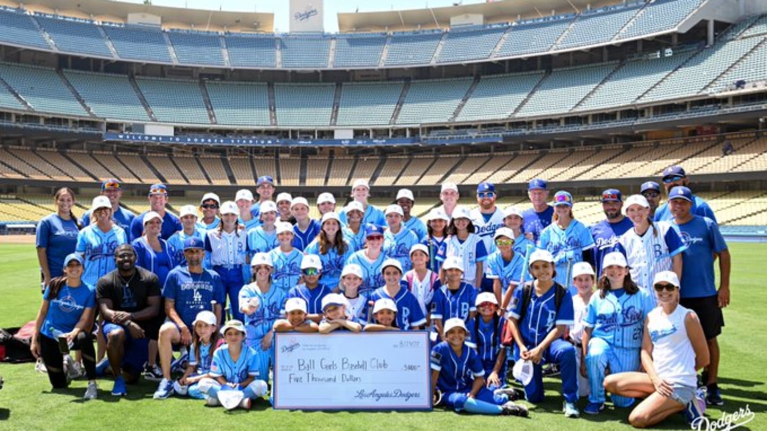 A group photo of girls and instructors in the sunshine on the Dodger Stadium grass