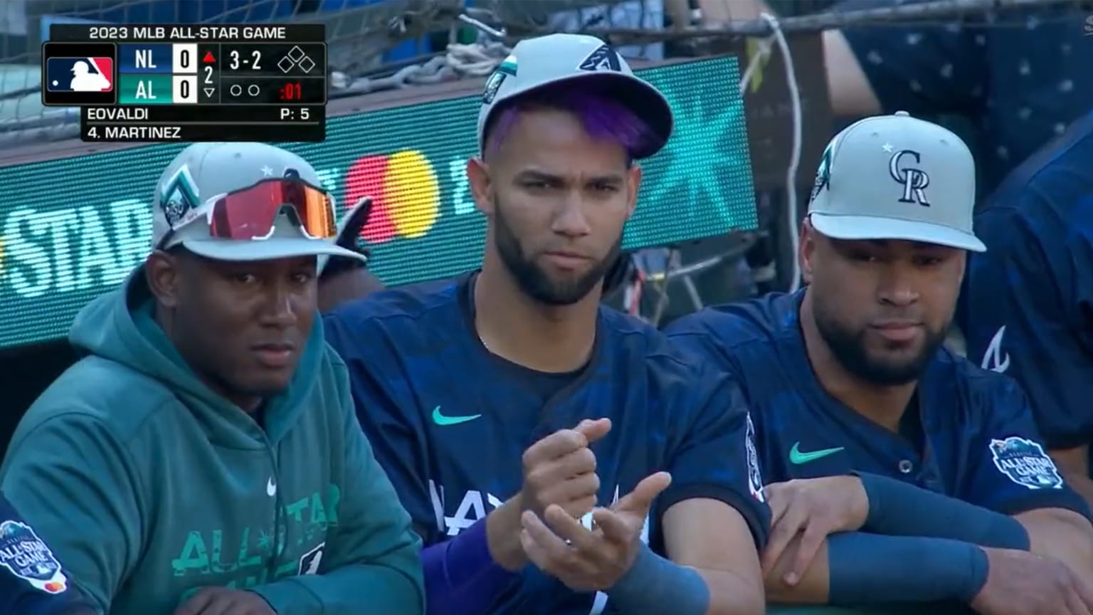Lourdes Gurriel Jr. leans on the dugout railing with two All-Star teammates