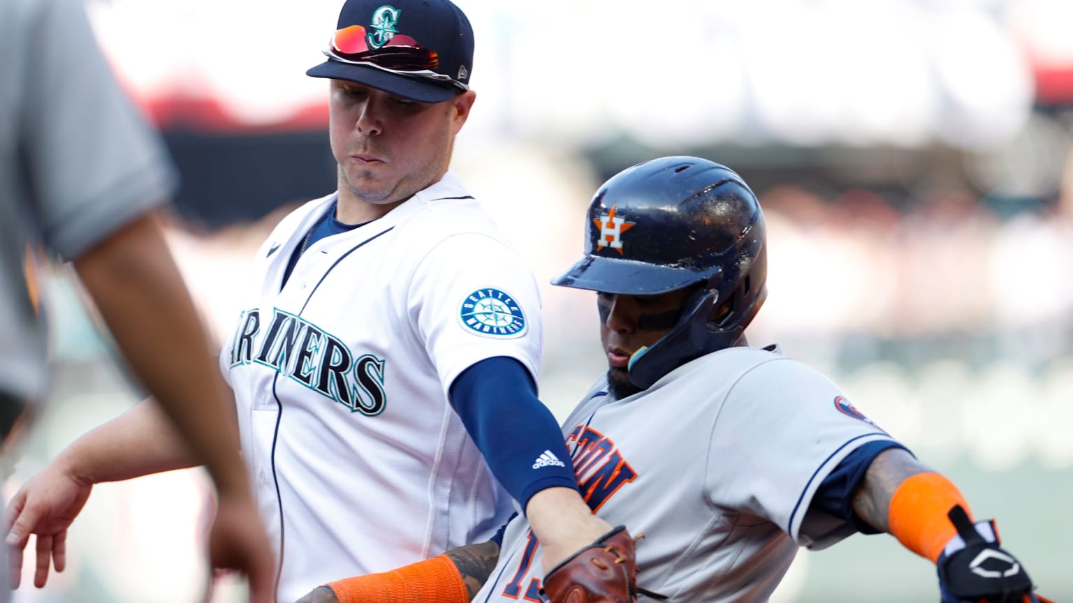 A Mariners player reaches across the chest of an Astros player, tagging him