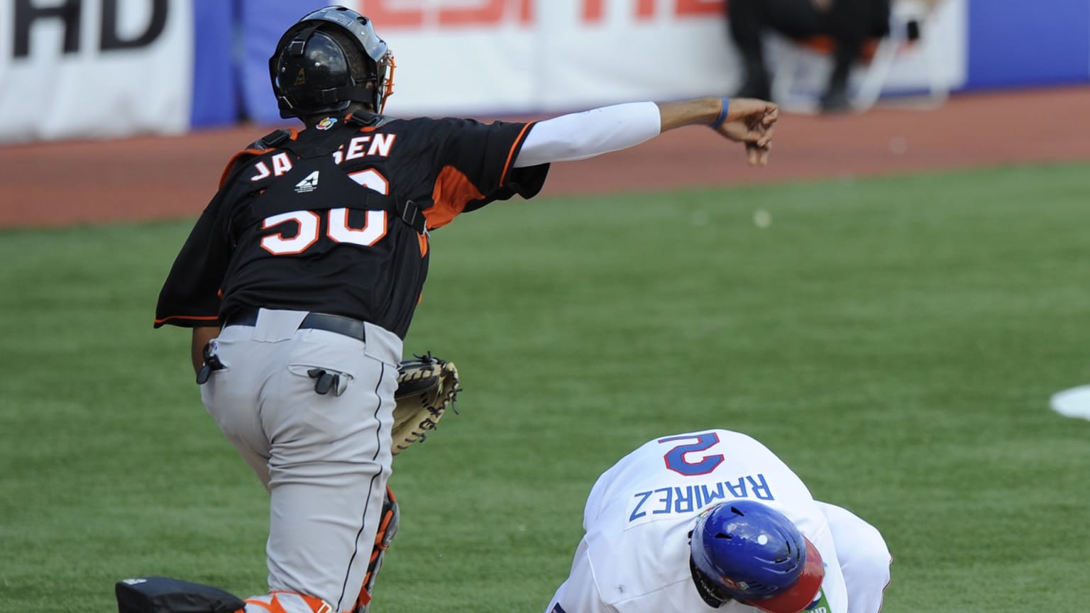 A catcher in a black jersey throws to third over a ducking batter