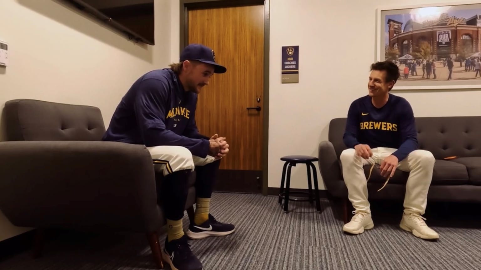 Brice Turang sits on a chair in an office listening to his manager, Craig Counsell, seated nearby on a couch