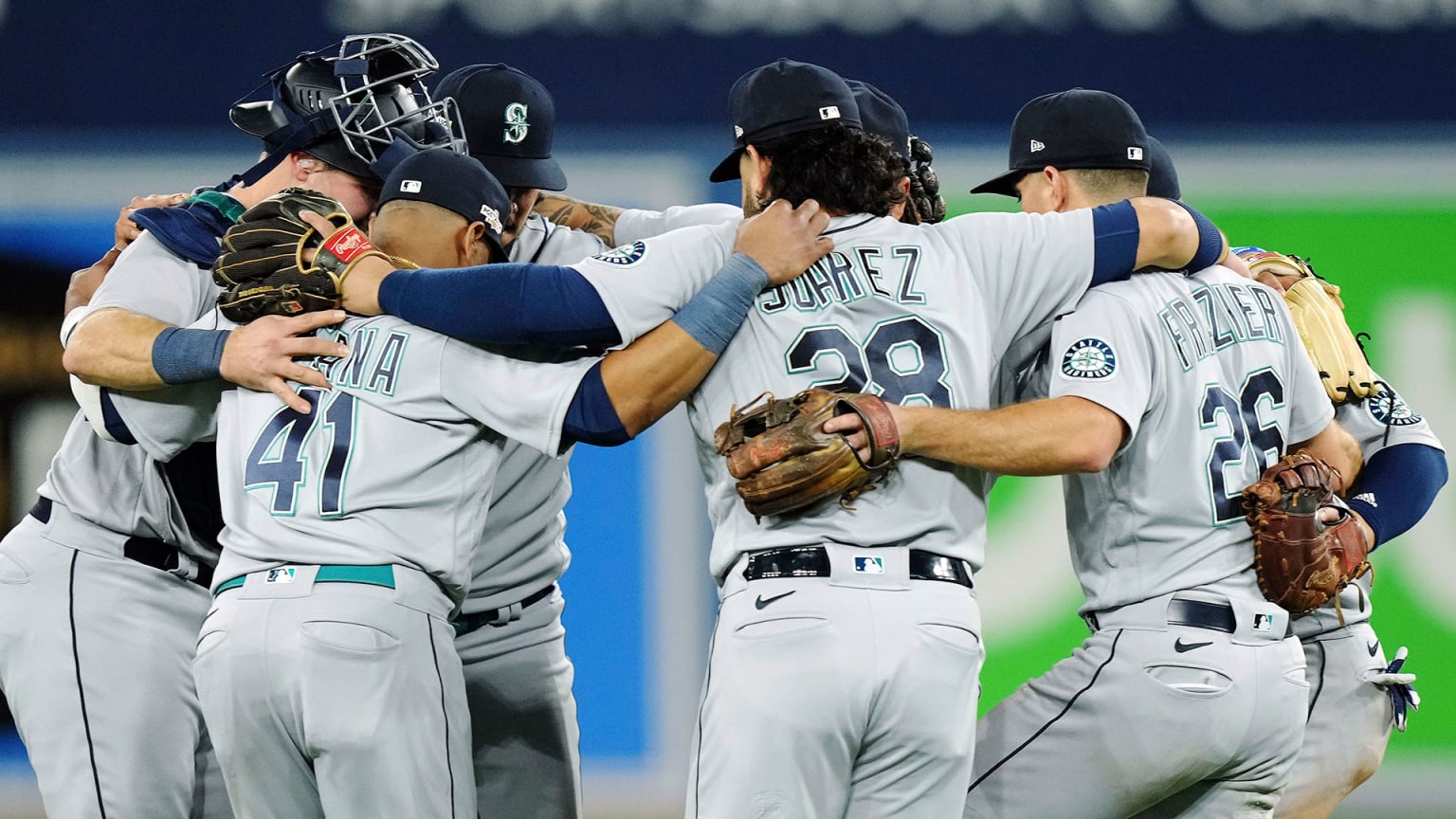 Mariners players form a circle, arms around each other, to celebrate their victory