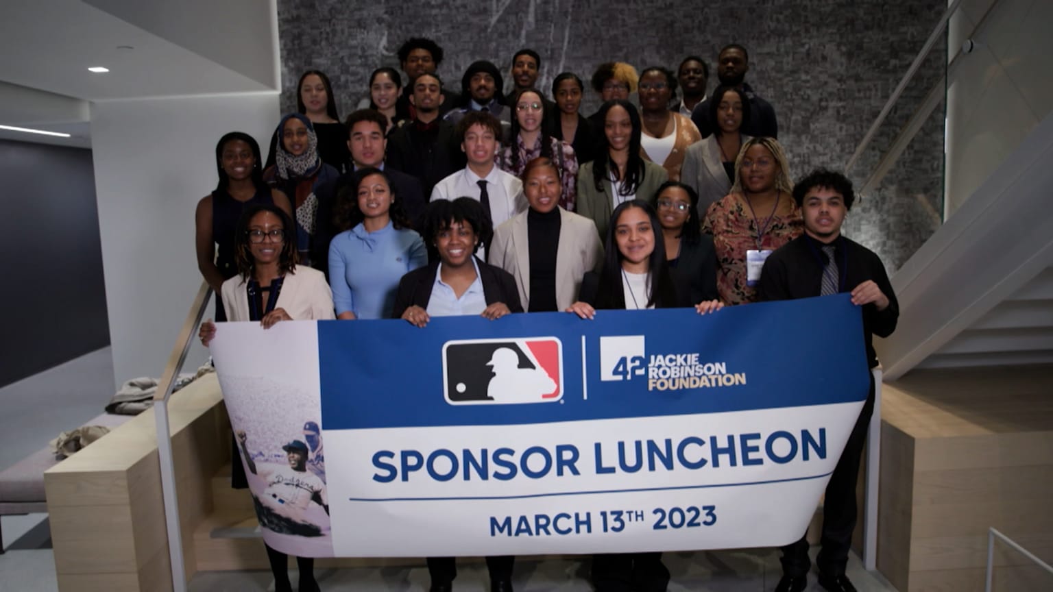 A group of college students behind a banner reading ''Sponsor Luncheon''