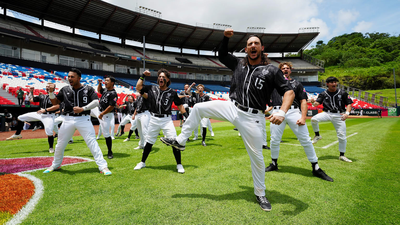 Baseball players in black jerseys and white pants perform a dance ritual on the field before a game