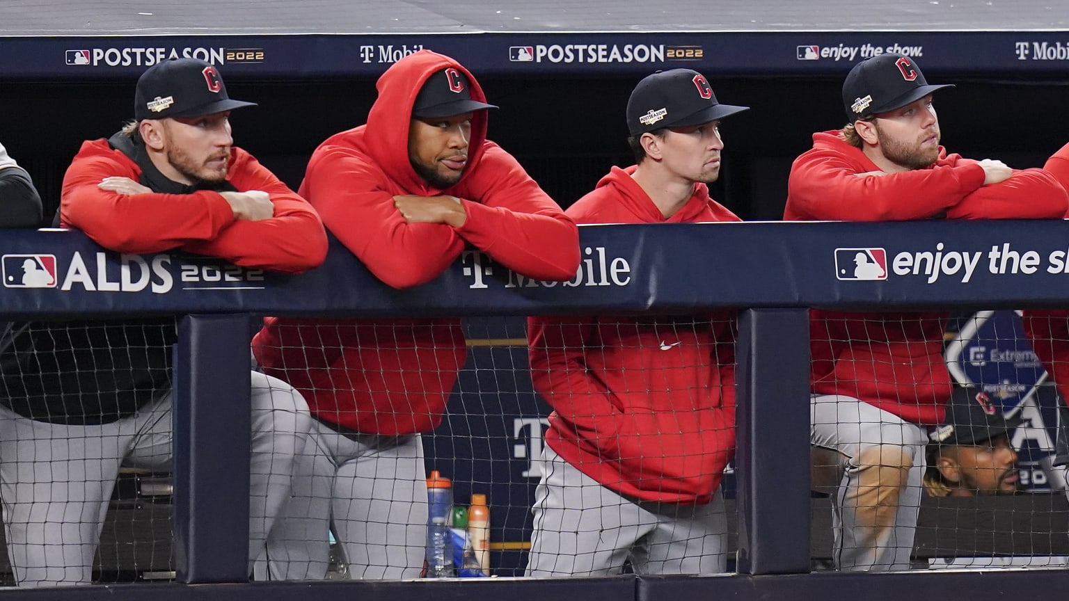 Four Cleveland Guardians players standing in the dugout