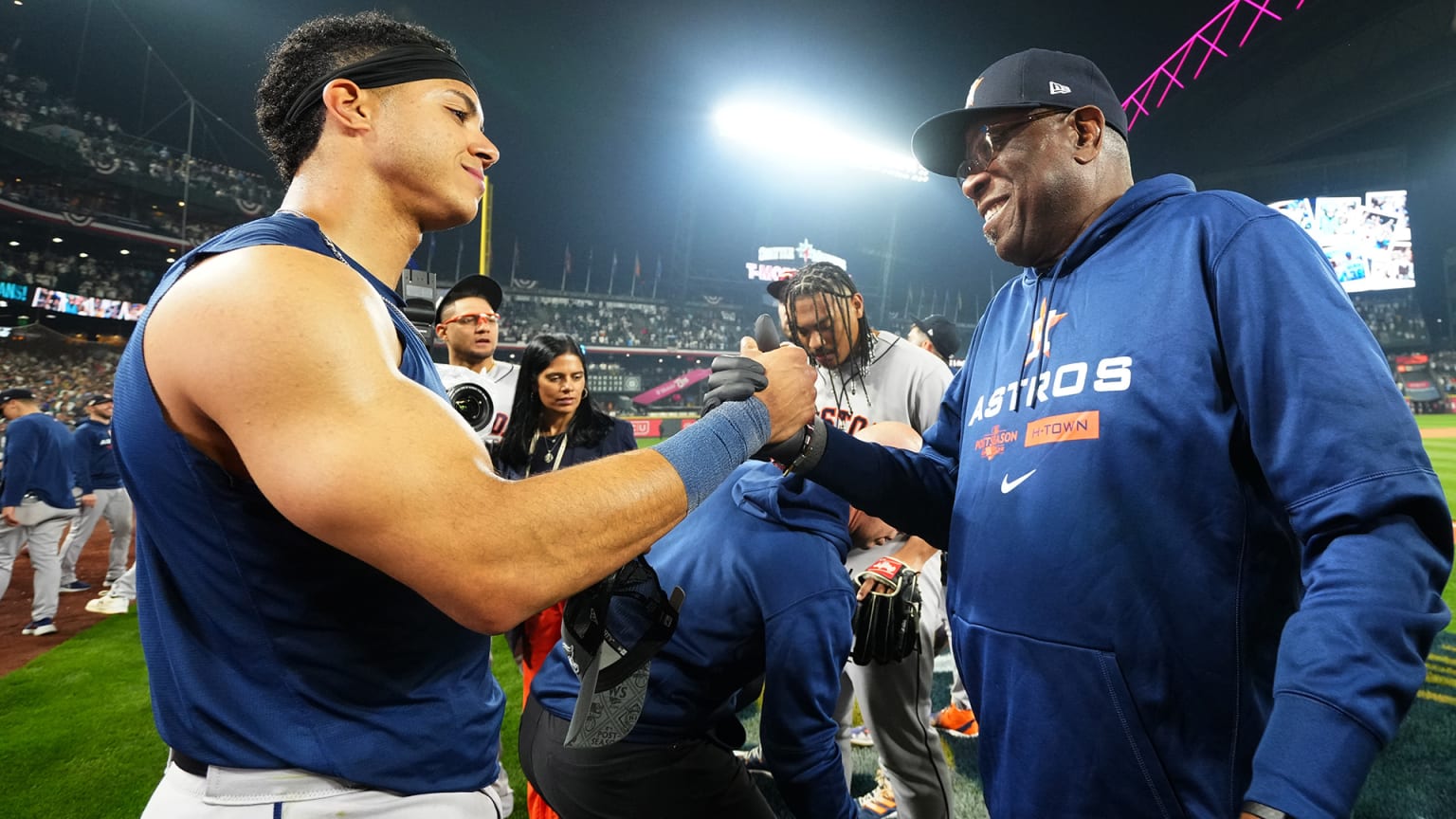 A player in a sleeveless T-shirt clasps hands with manager Dusty Baker in a sweatshirt