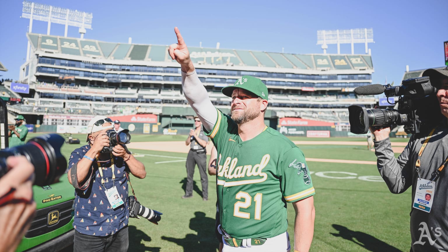 Wearing a green jersey reading ''Oakland,'' Stephen Vogt points to the stands from the field, surrounded by photographers after the game