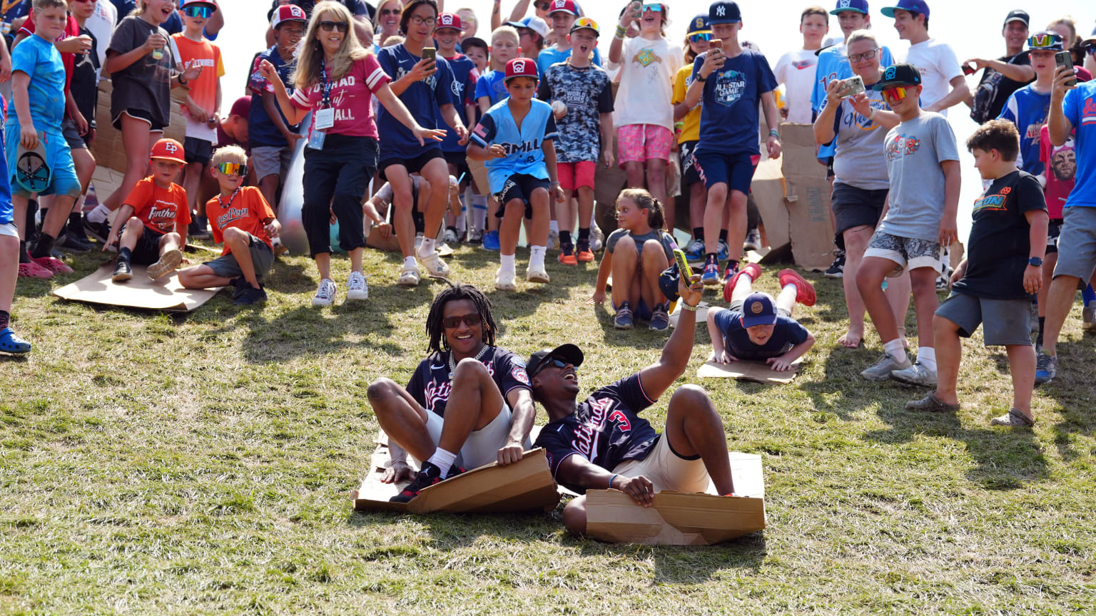 CJ Abrams and Jeter Downs slide down a hill on pieces of cardboard