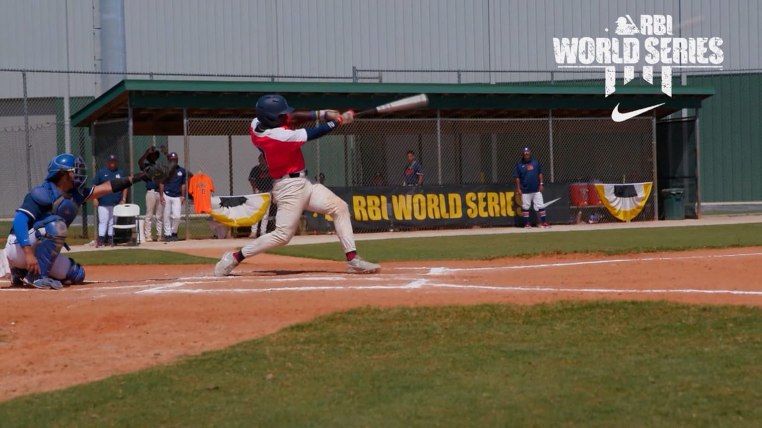 A batter swings the bat as the catcher reaches for the ball