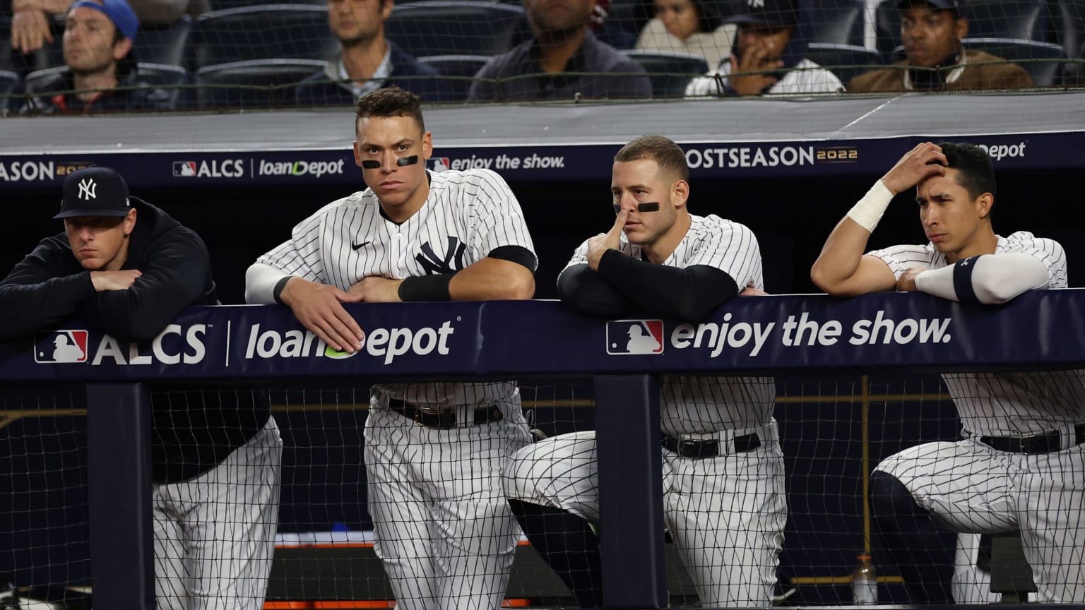 Four Yankees players look on dejectedly from the dugout railing