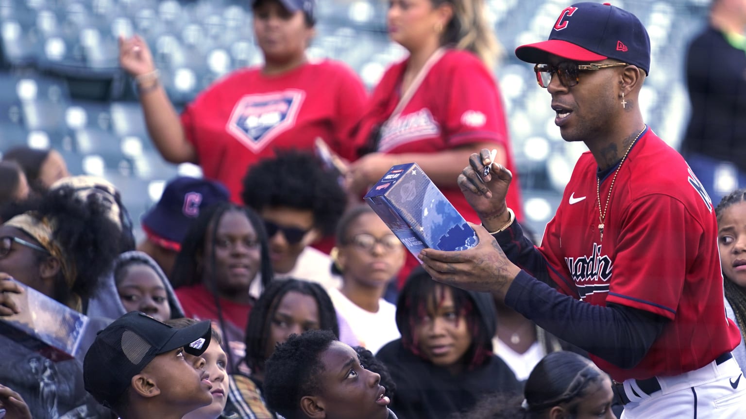 Kid Cudi in a Guardians uniform signs a bobblehead for a fan at Progressive Field