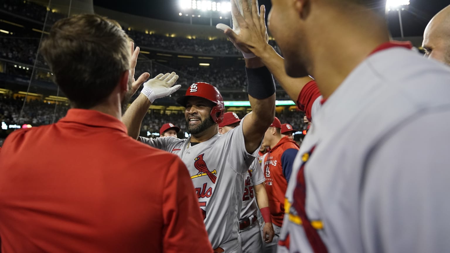 Albert Pujols stands among Cardinals teammates, smiling as he receives high-fives