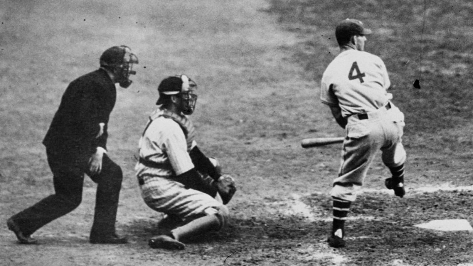 A batter lifts his front leg ready to swing as a catcher and umpire watch the pitch