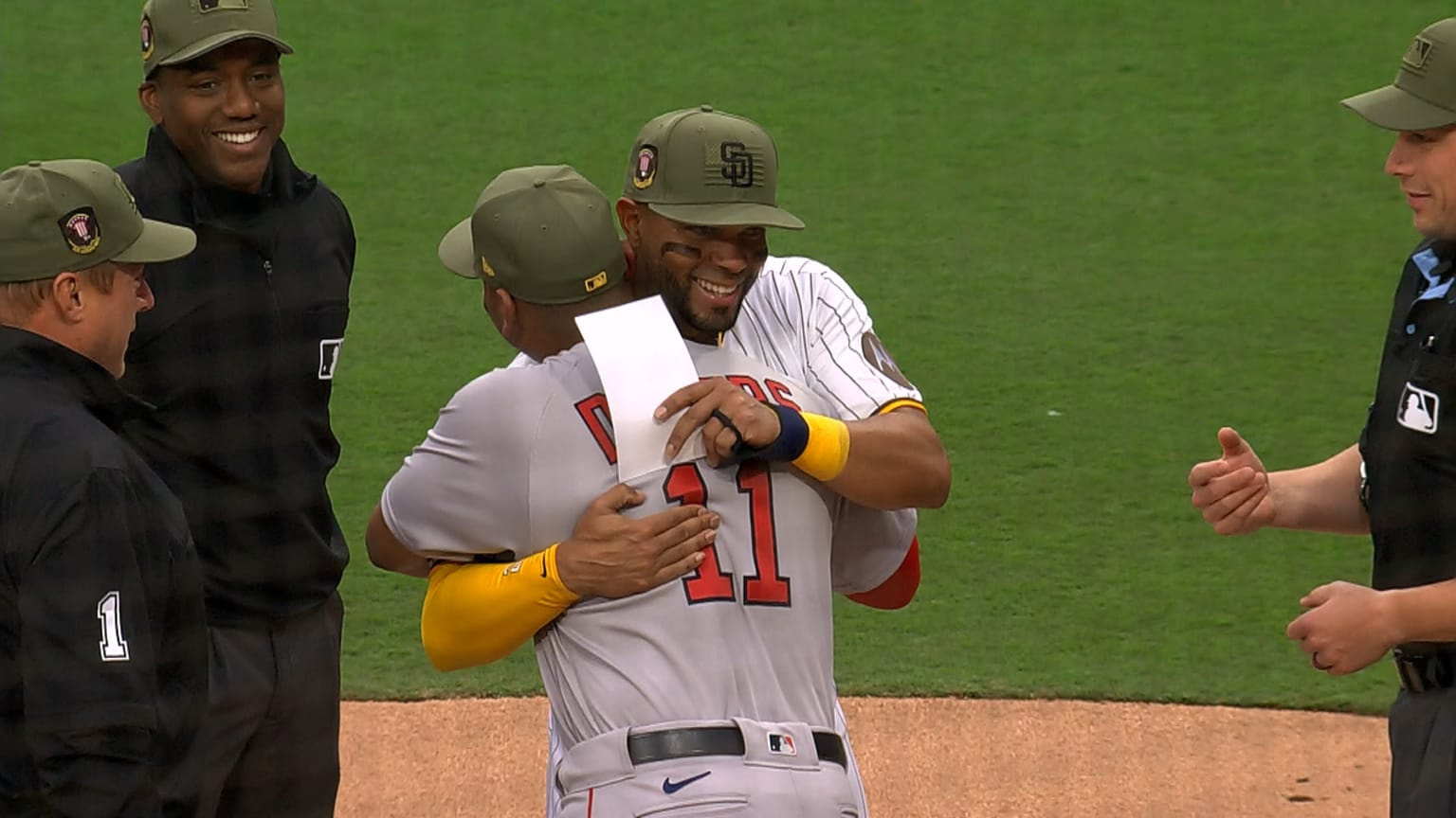 Rafael Devers and Xander Bogaerts hug before the game as umpires look on