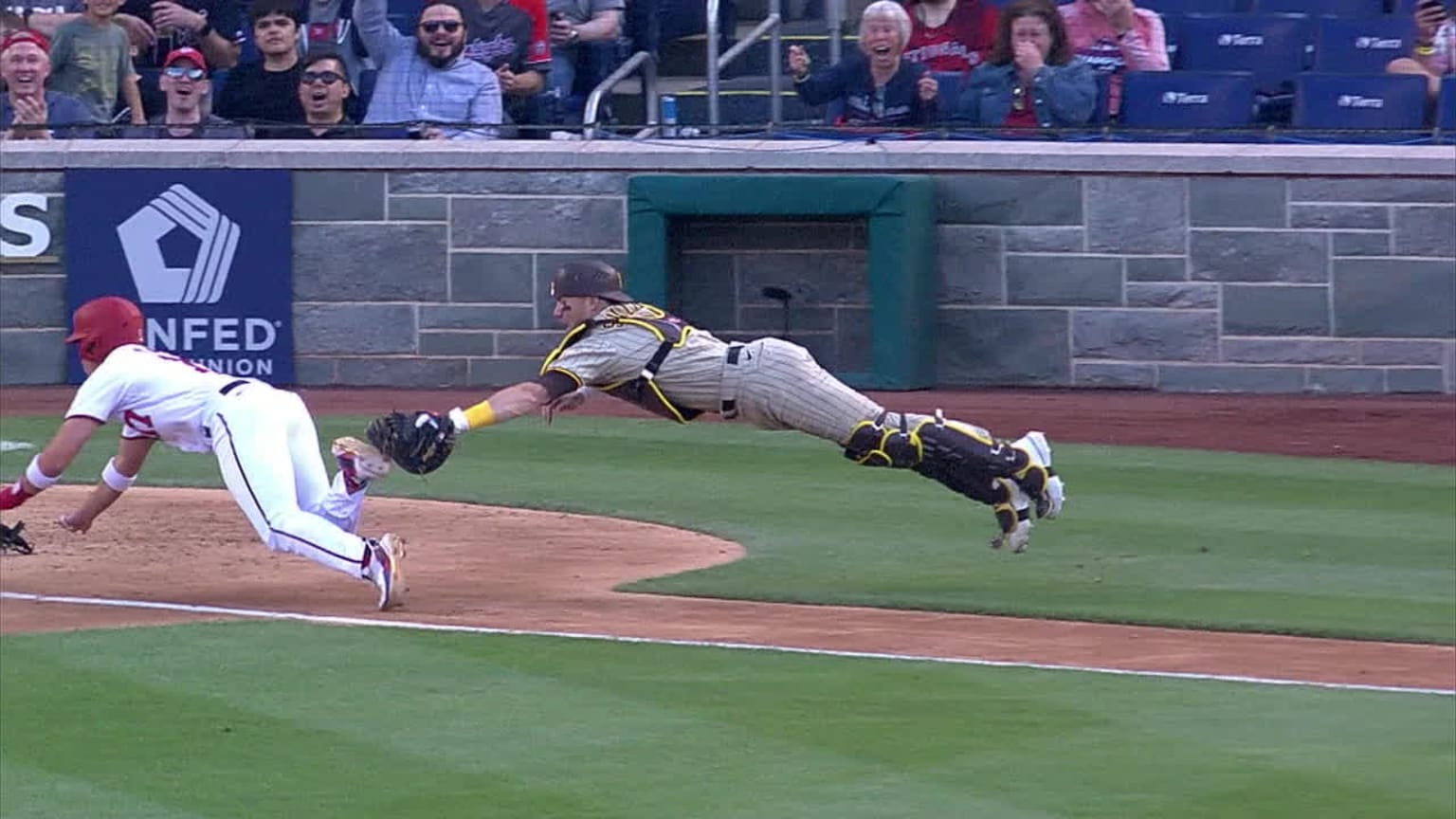 A catcher in midair reaching to tag a diving runner on the foot