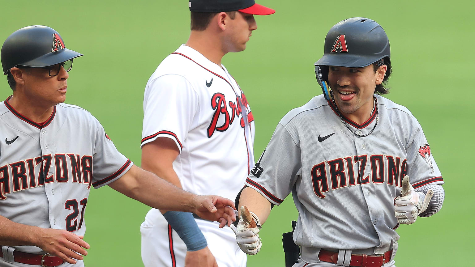 Corbin Carroll smiles while celebrating with his third-base coach