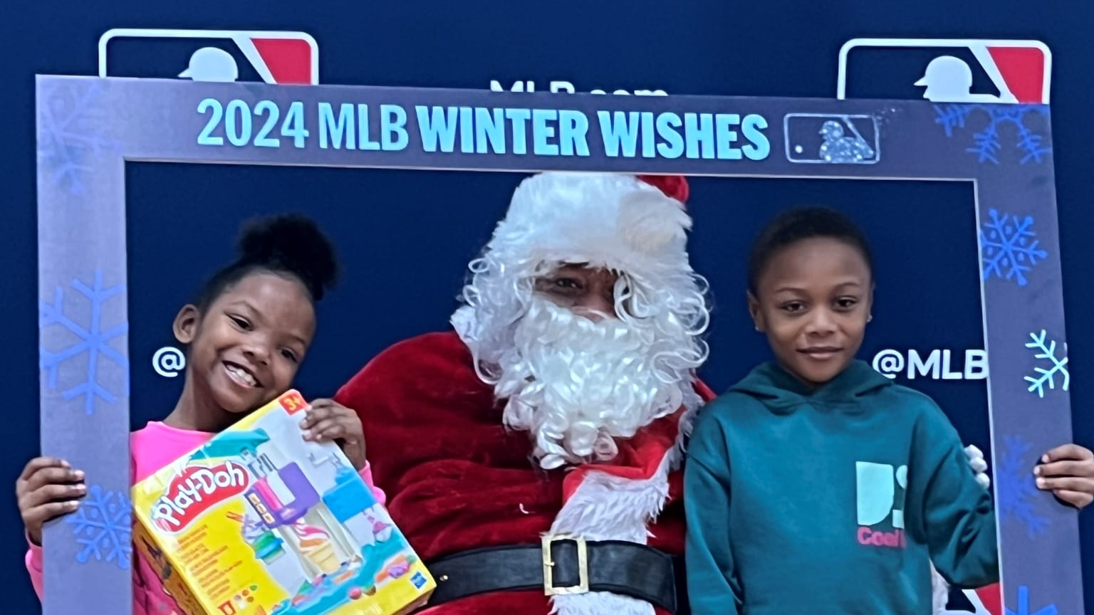 Two children take a photo with Santa Claus