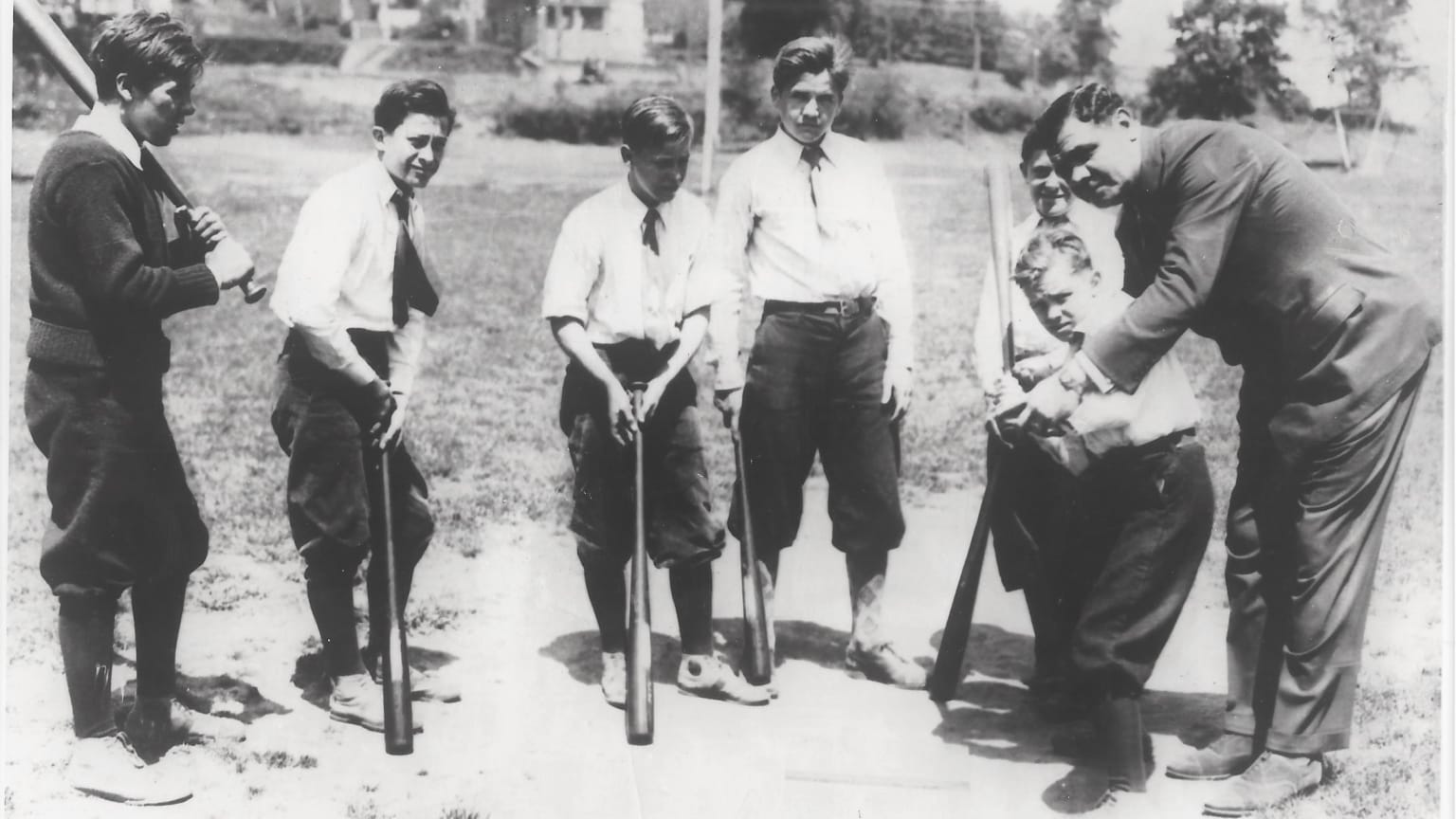 Babe Ruth shows a young boy how to hit while five of his friends look on