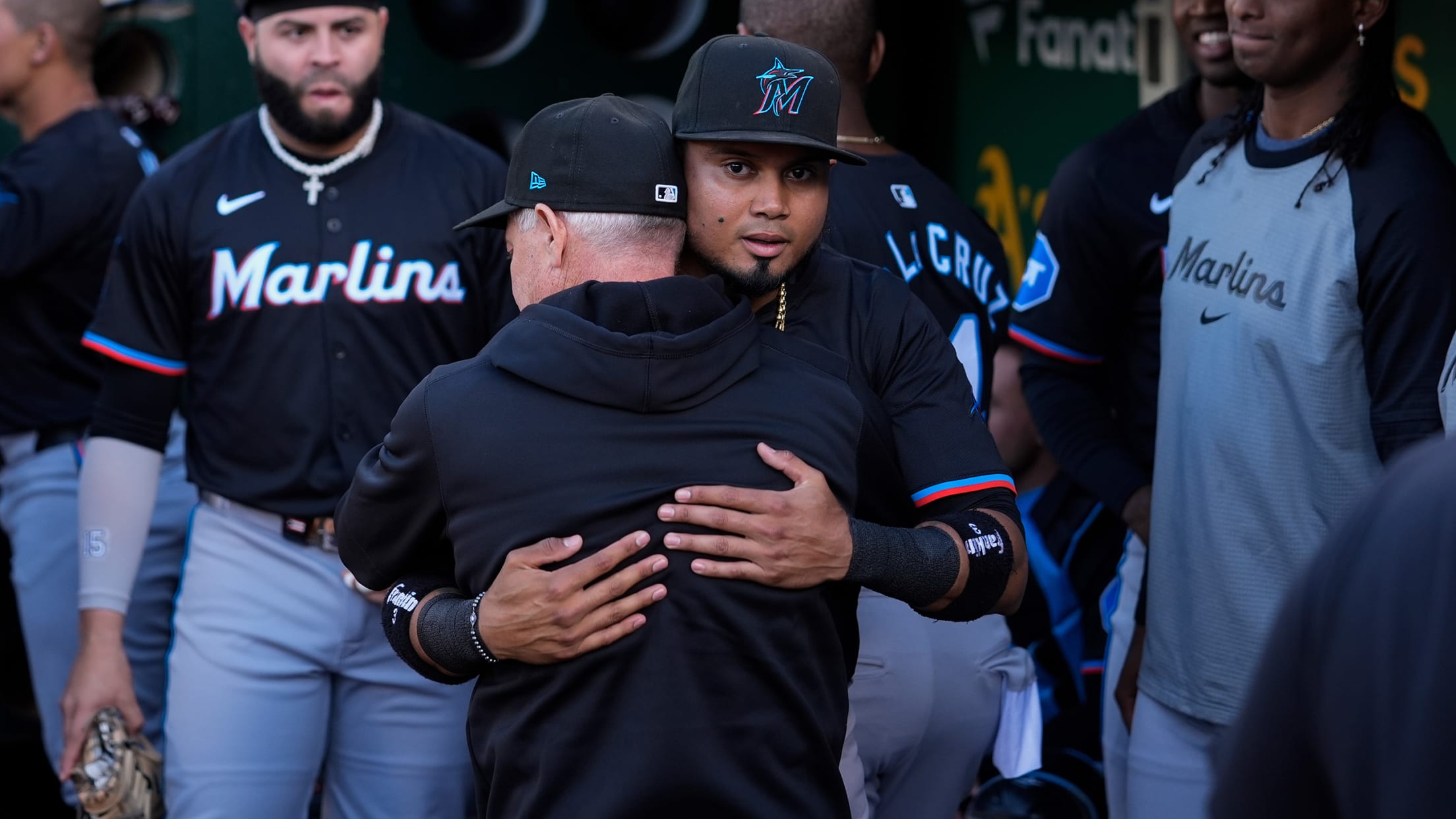 Luis Arraez hugs teammates in the dugout after he was pulled from the lineup just before first pitch