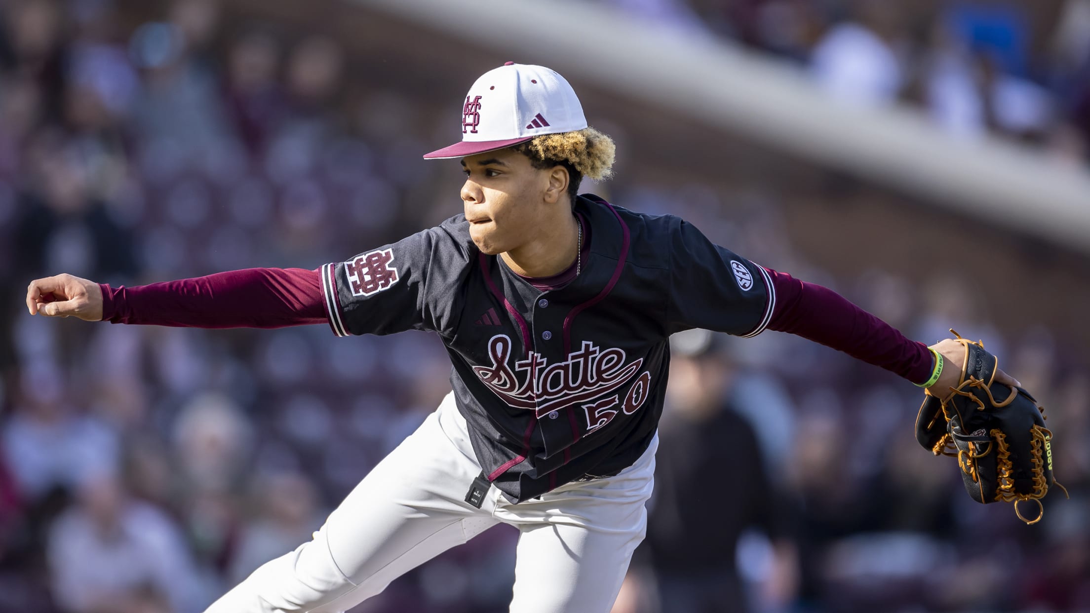 A pitcher in a black jersey and white pants follows through