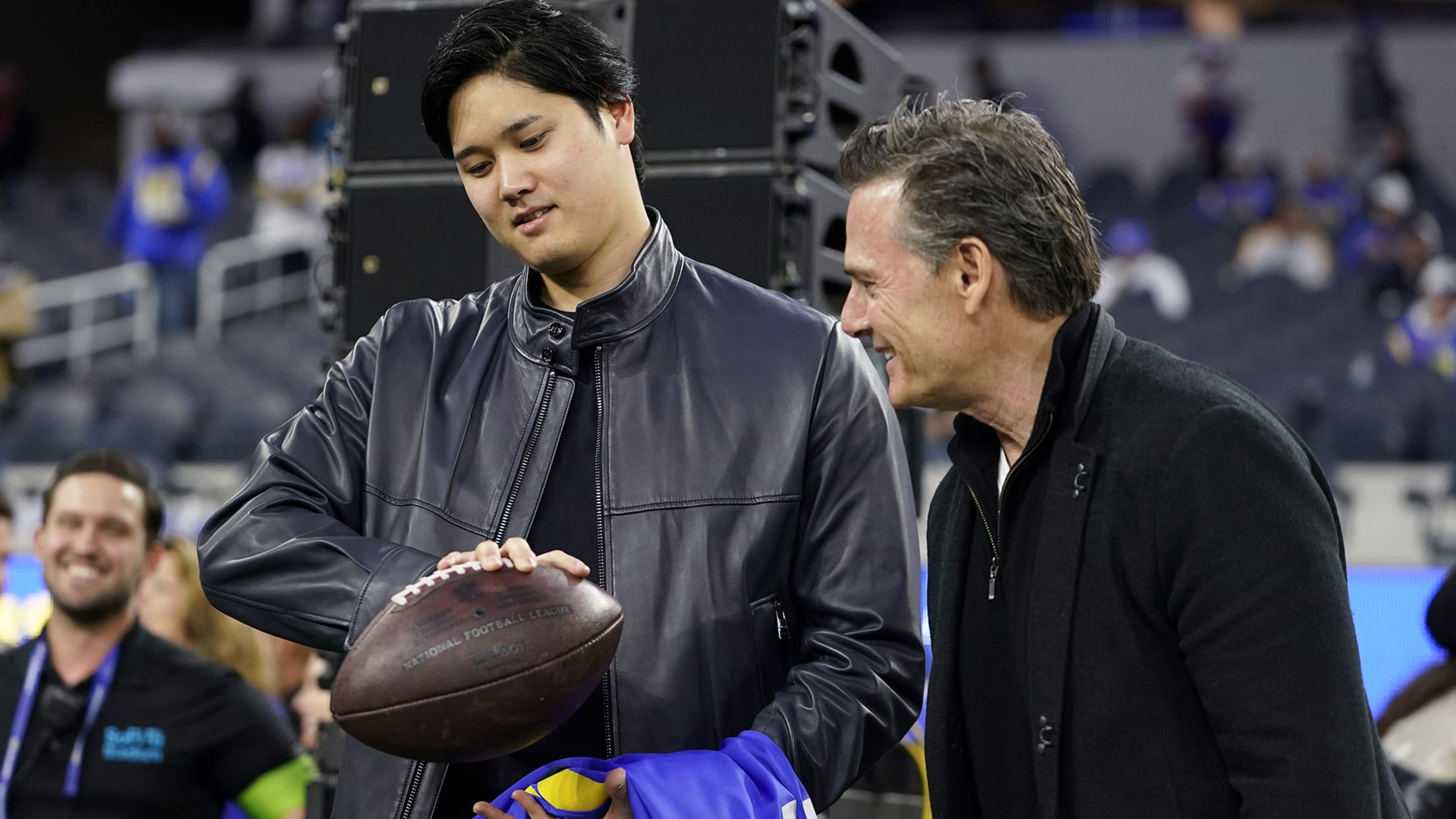 Shohei Ohtani holds a football on the sidelines before the Rams game