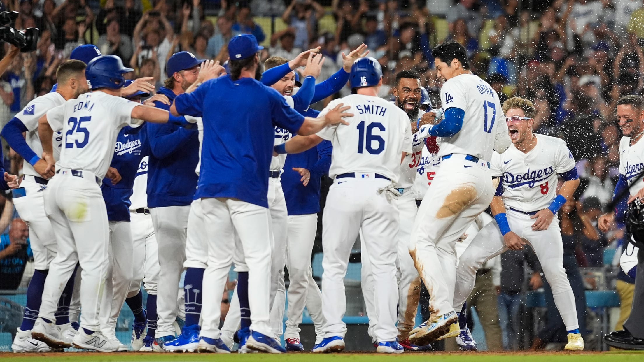 Shohei Ohtani leaps into a mob of Dodgers at home plate after hitting a walk-off grand slam