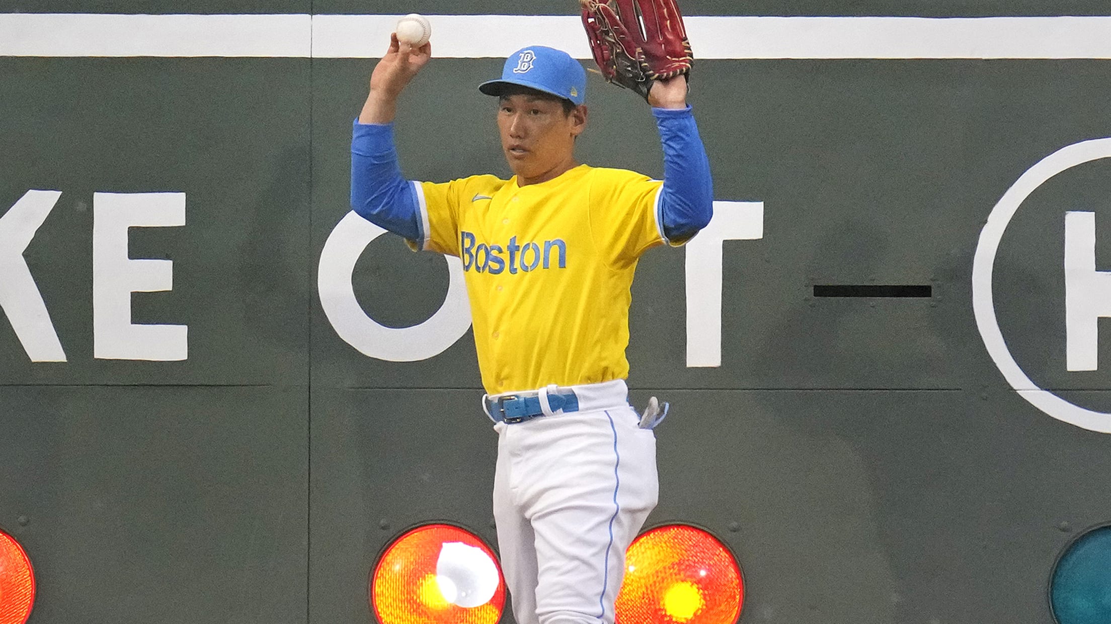 Masataka Yoshida holds up his hands in front of a broken light on the Green Monster