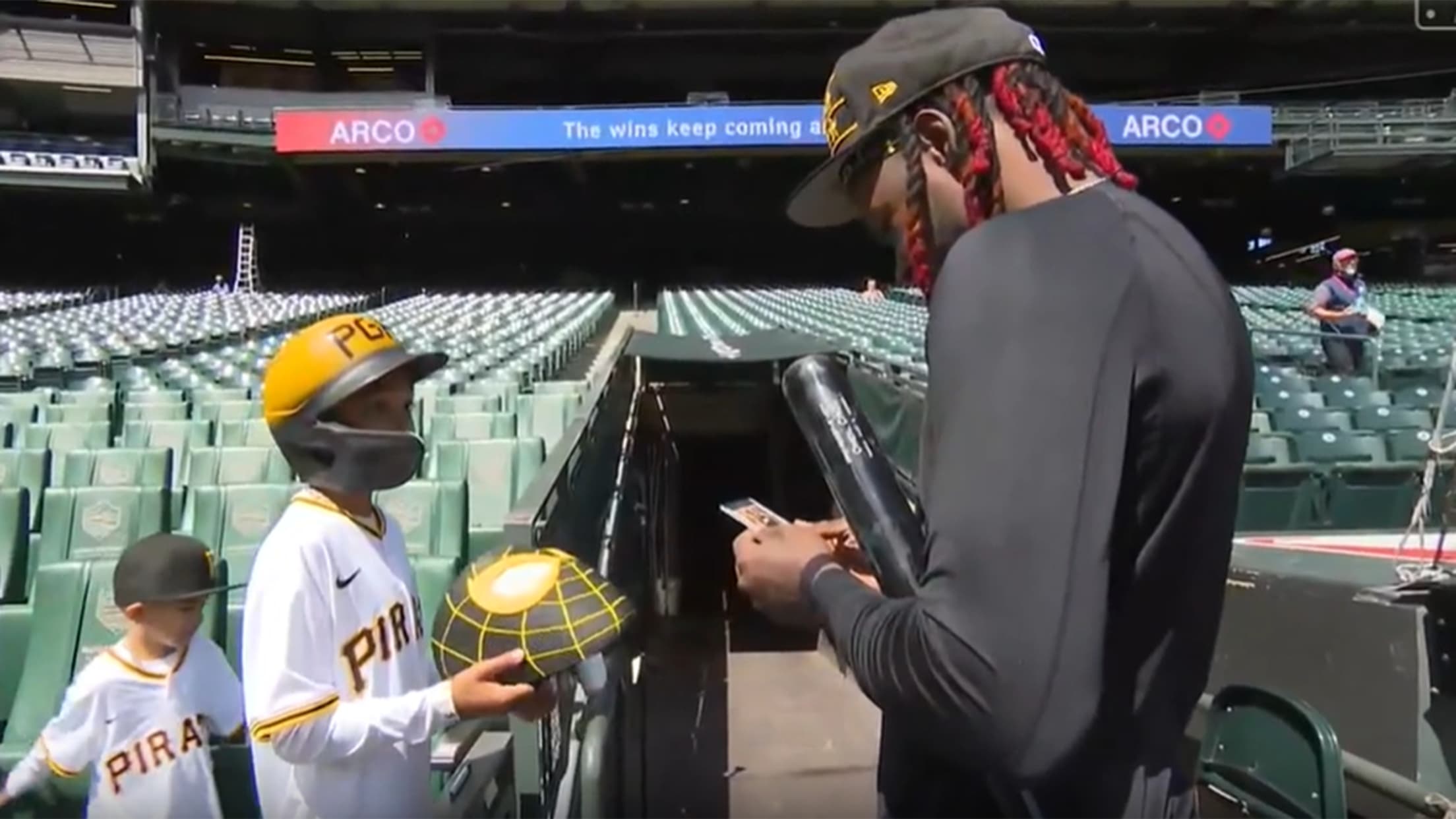 A young fan prepares to hand Oneil Cruz a black-and-yellow Spider-Man mask