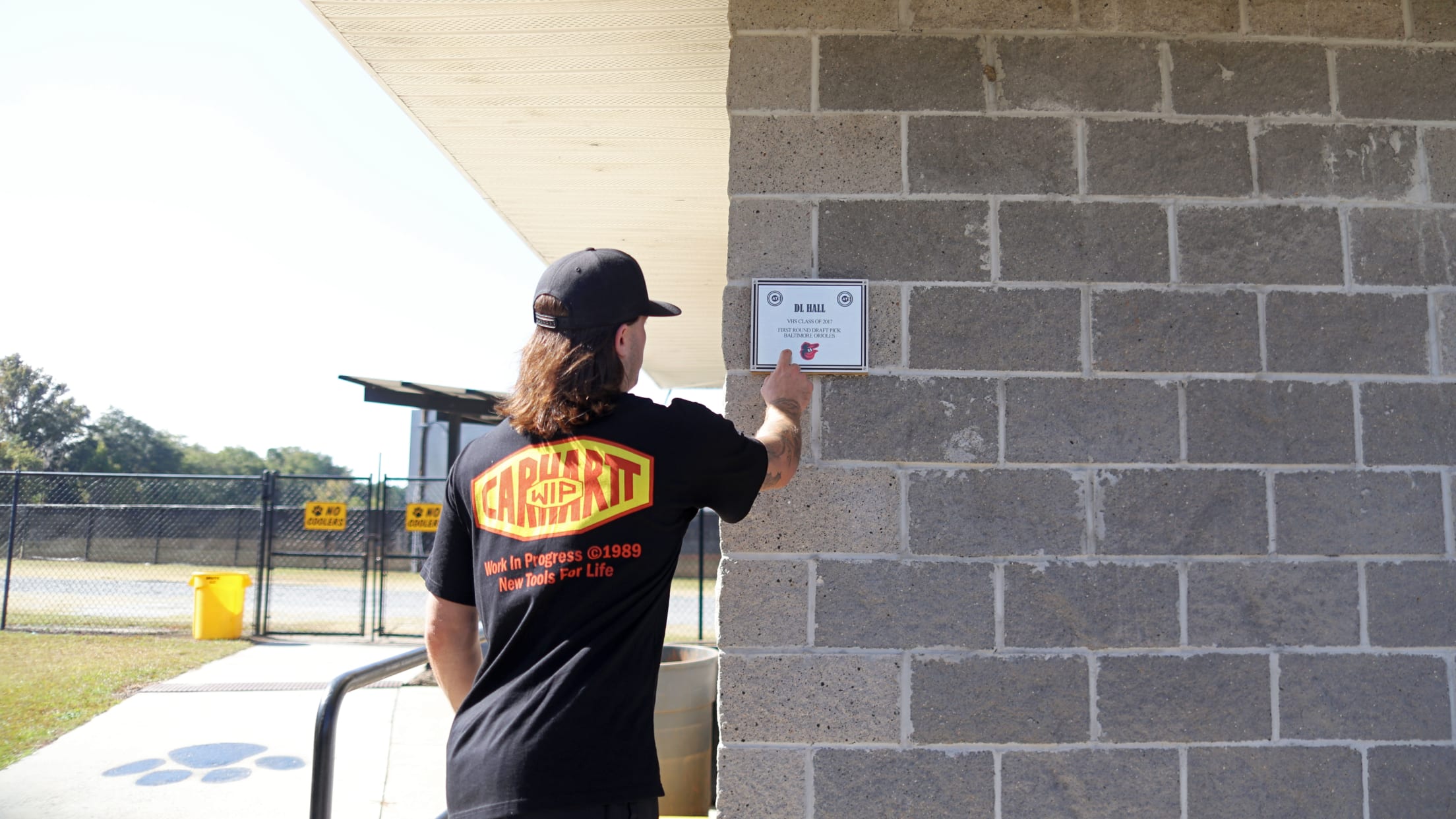 Hall pointing to his plaque on the wall of the concession stand at the Valdosta Wildcat baseball stadium.  Hall is one of two professional baseball players from Valdosta High School.