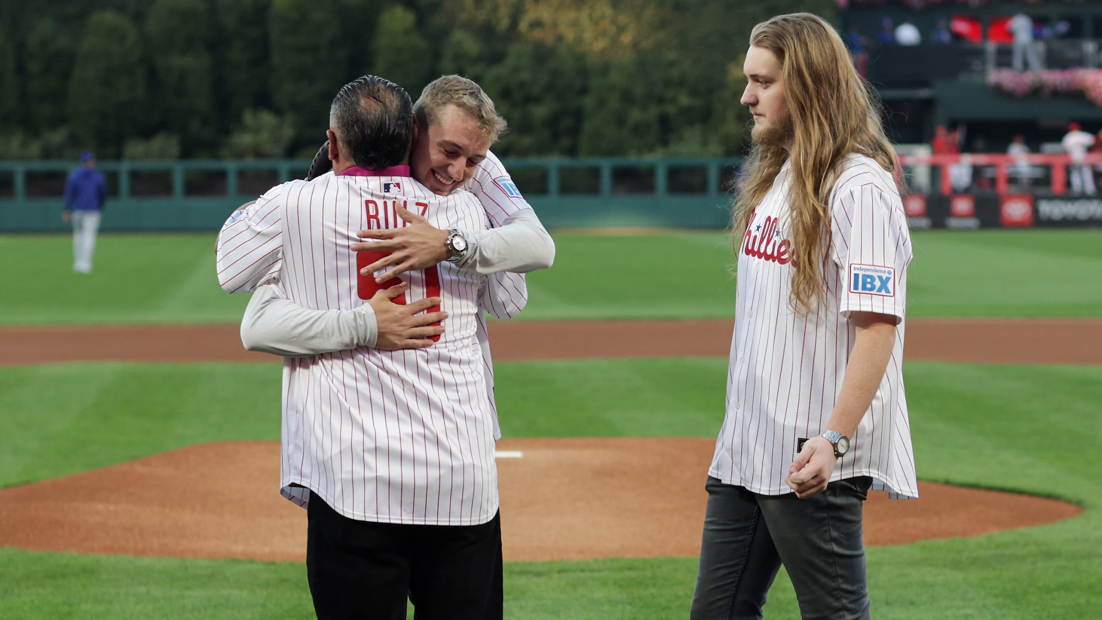 Braden Halladay hugs Carlos Ruiz as Ryan Halladay looks on