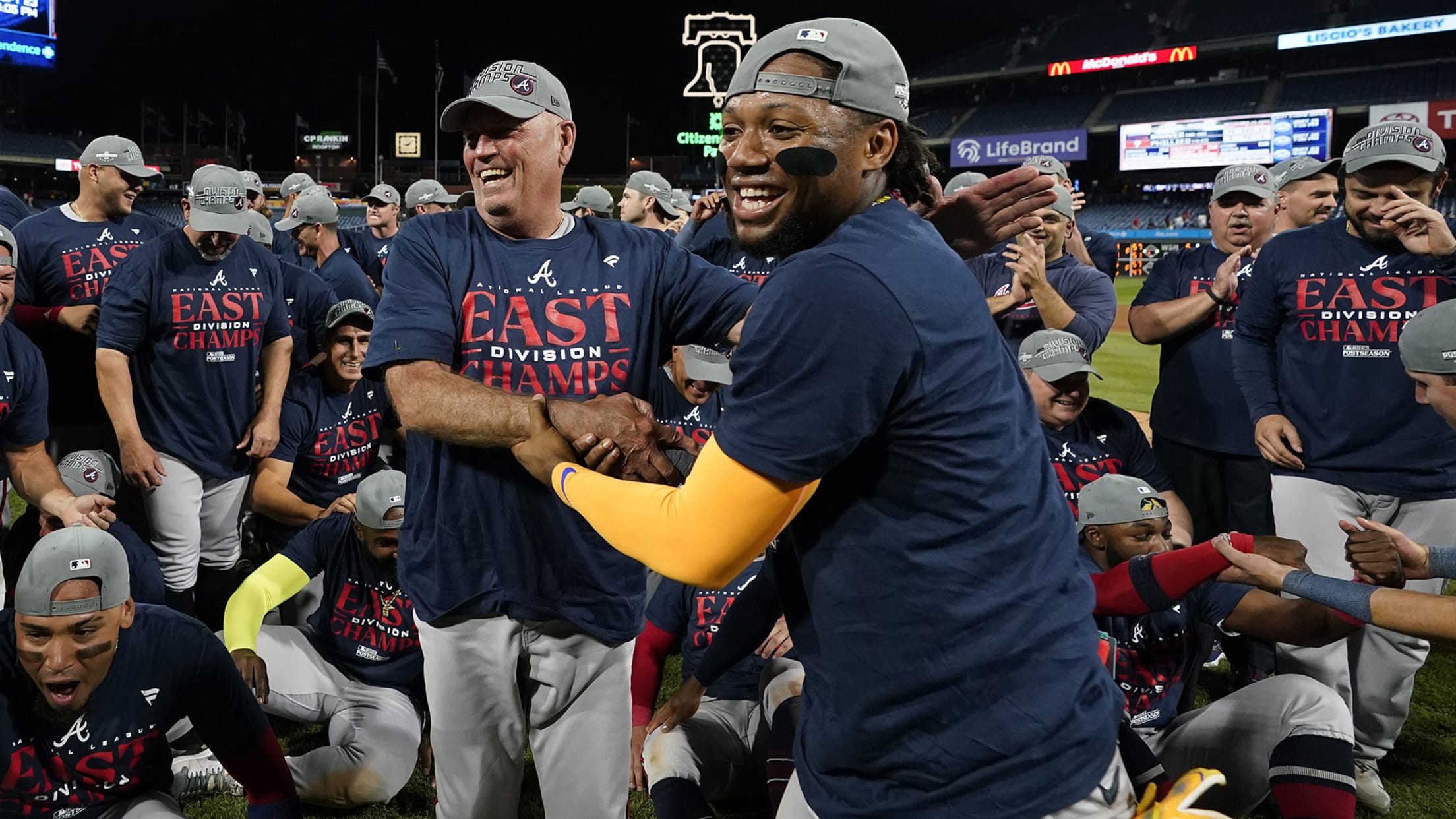 Brian Snitker and Ronald Acuña Jr. shake hands while the Braves celebrate on the field in Philadelphia