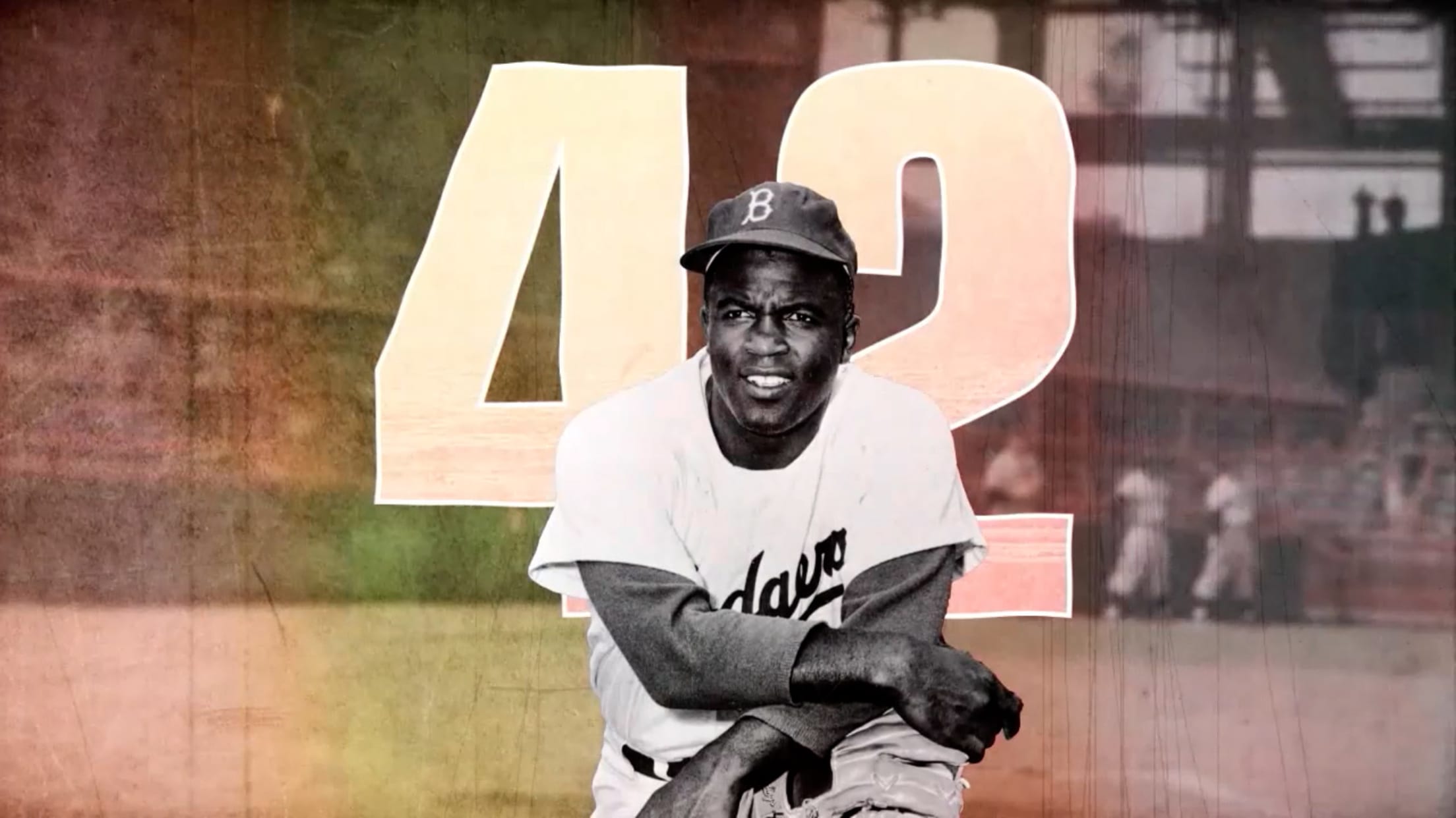 A black-and-white image of Jackie Robinson down on one knee, his arms crossed atop his glove, which rests on the other knee. The number 42 is behind him, and a grainy image of a ballpark serves as the backdrop
