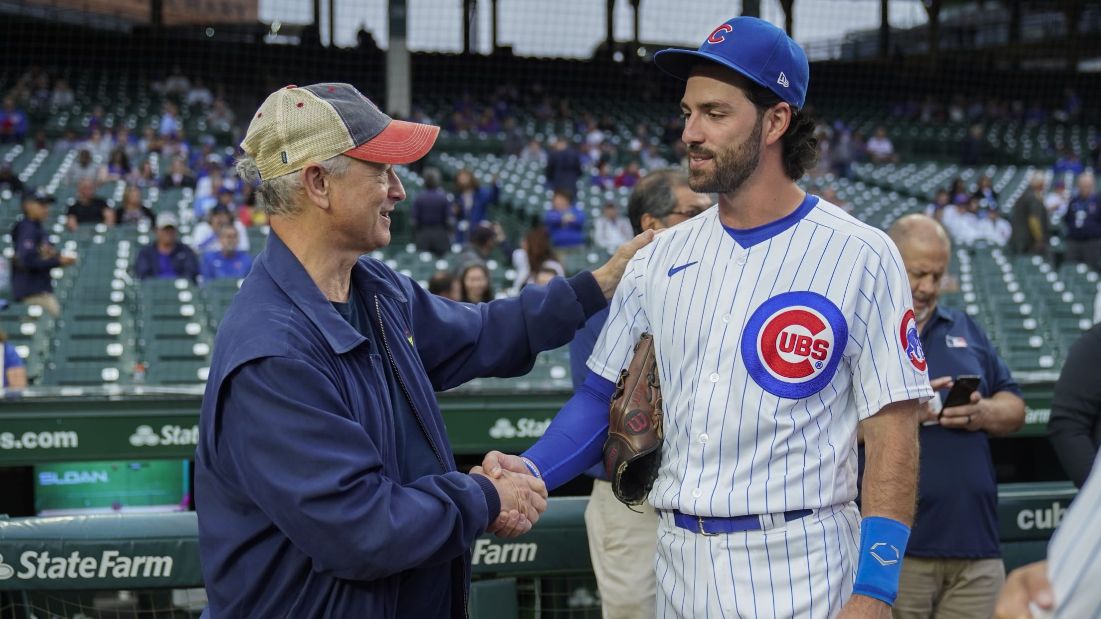 Actor Gary Sinise shakes hands with Cubs shortstop Dansby Swanson on the field before a game