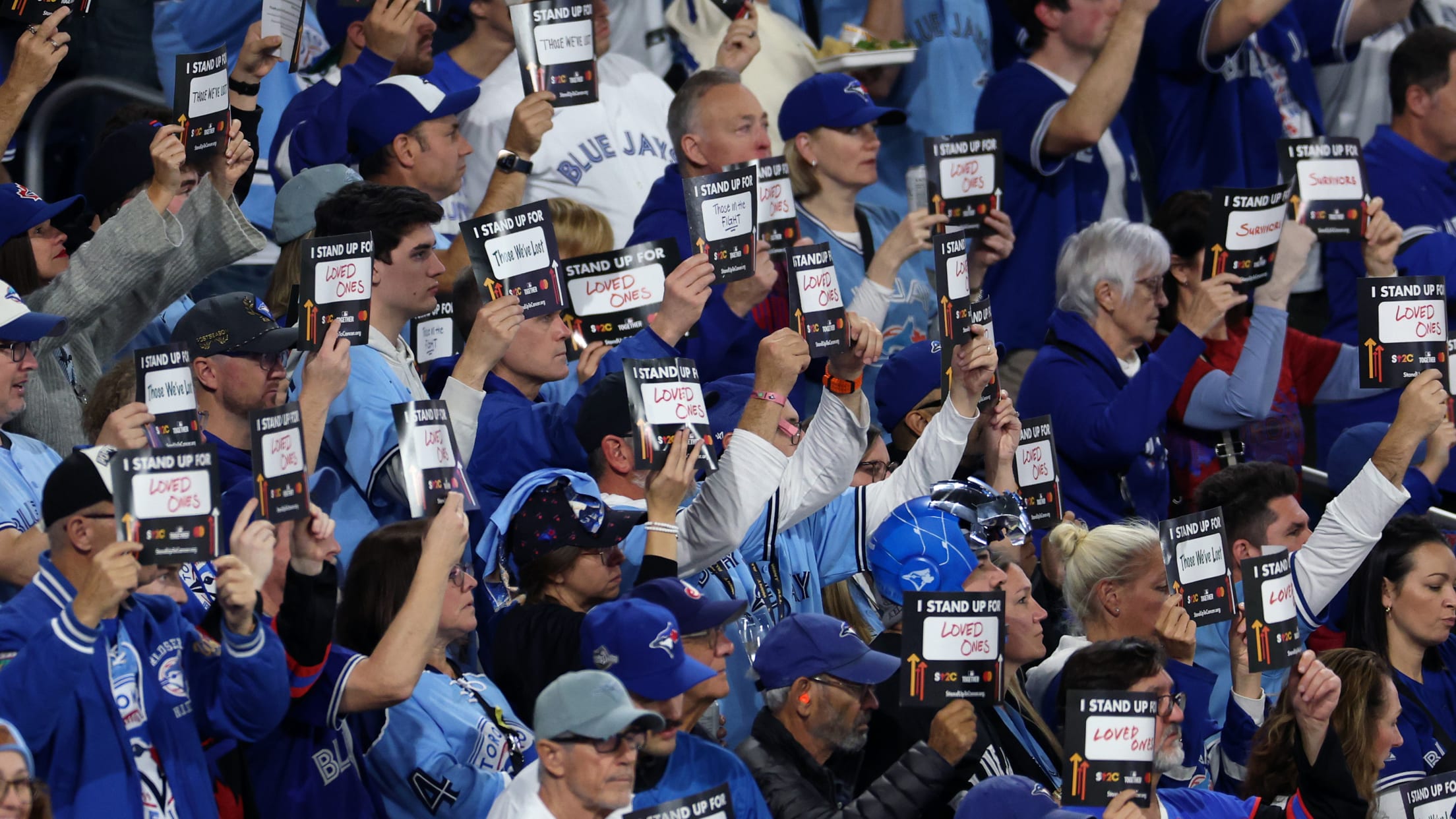 Fans hold up Stand Up To Cancer signs