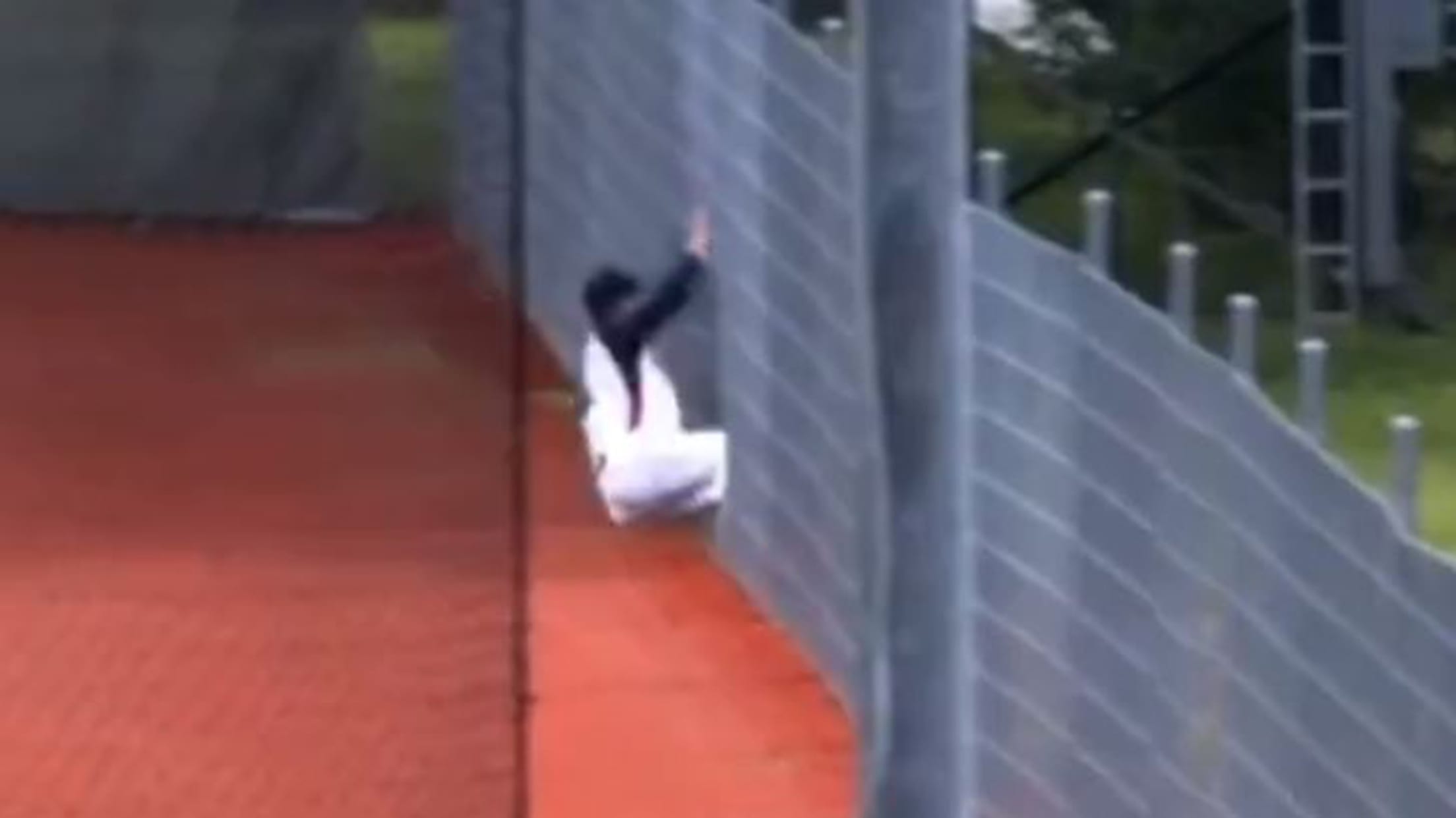 A screengrab of an outfielder sliding into a fence