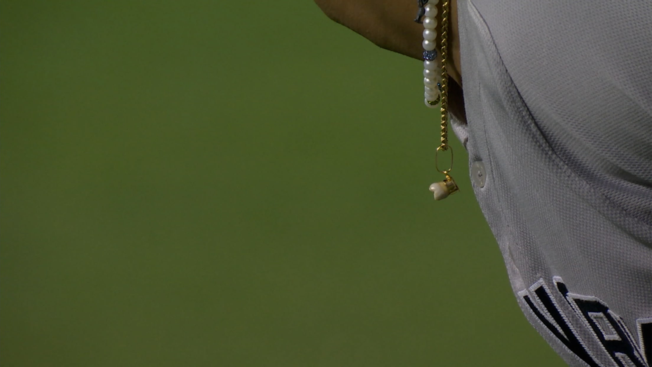 A necklace with a tooth on it dangles from a player's neck