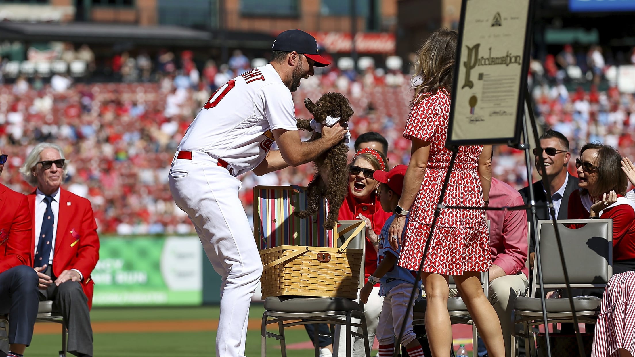 Adam Wainwright picks up a puppy during his on-field retirement ceremony