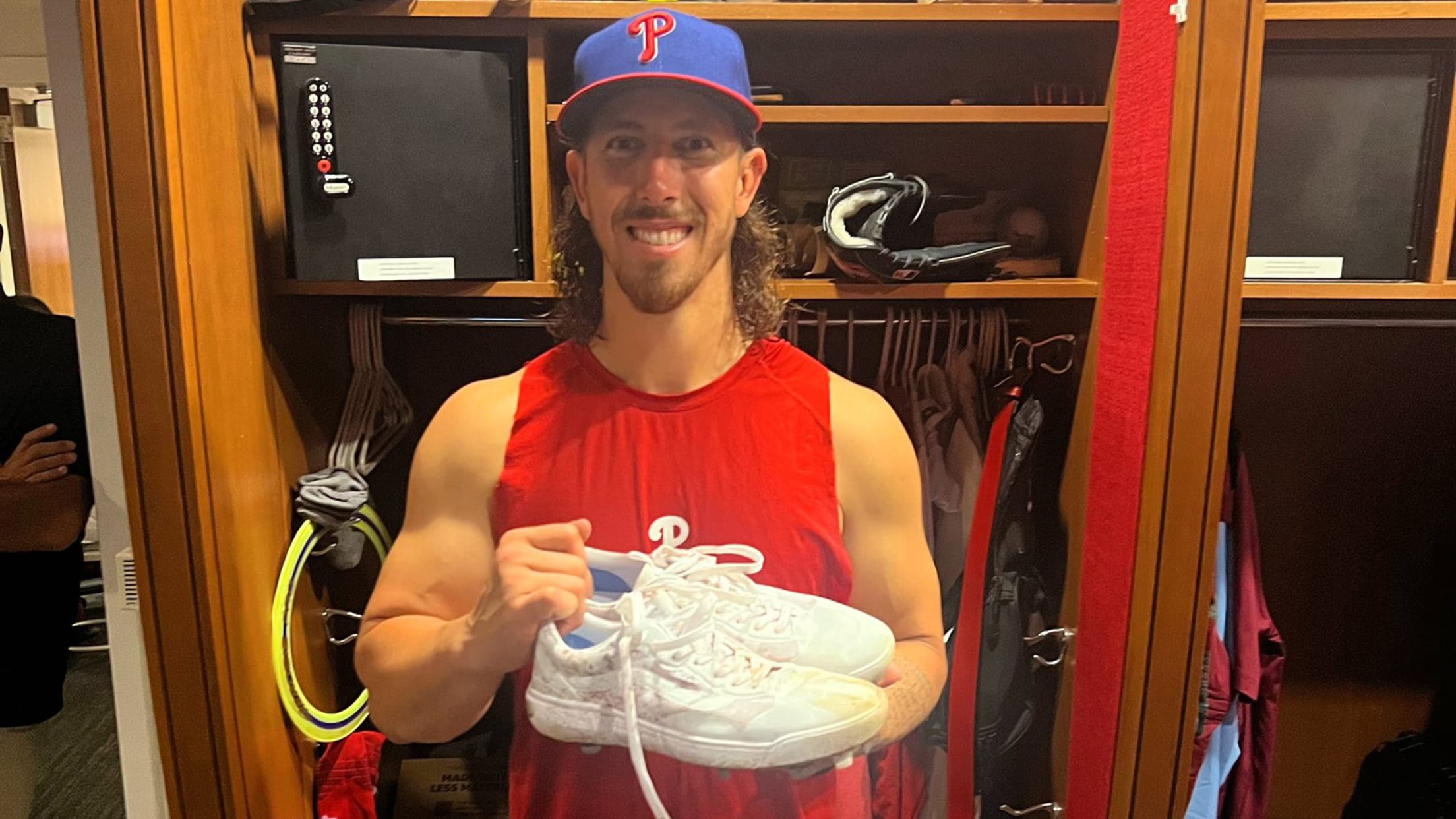 Michael Lorenzen holds up his white Vans cleats in the clubhouse