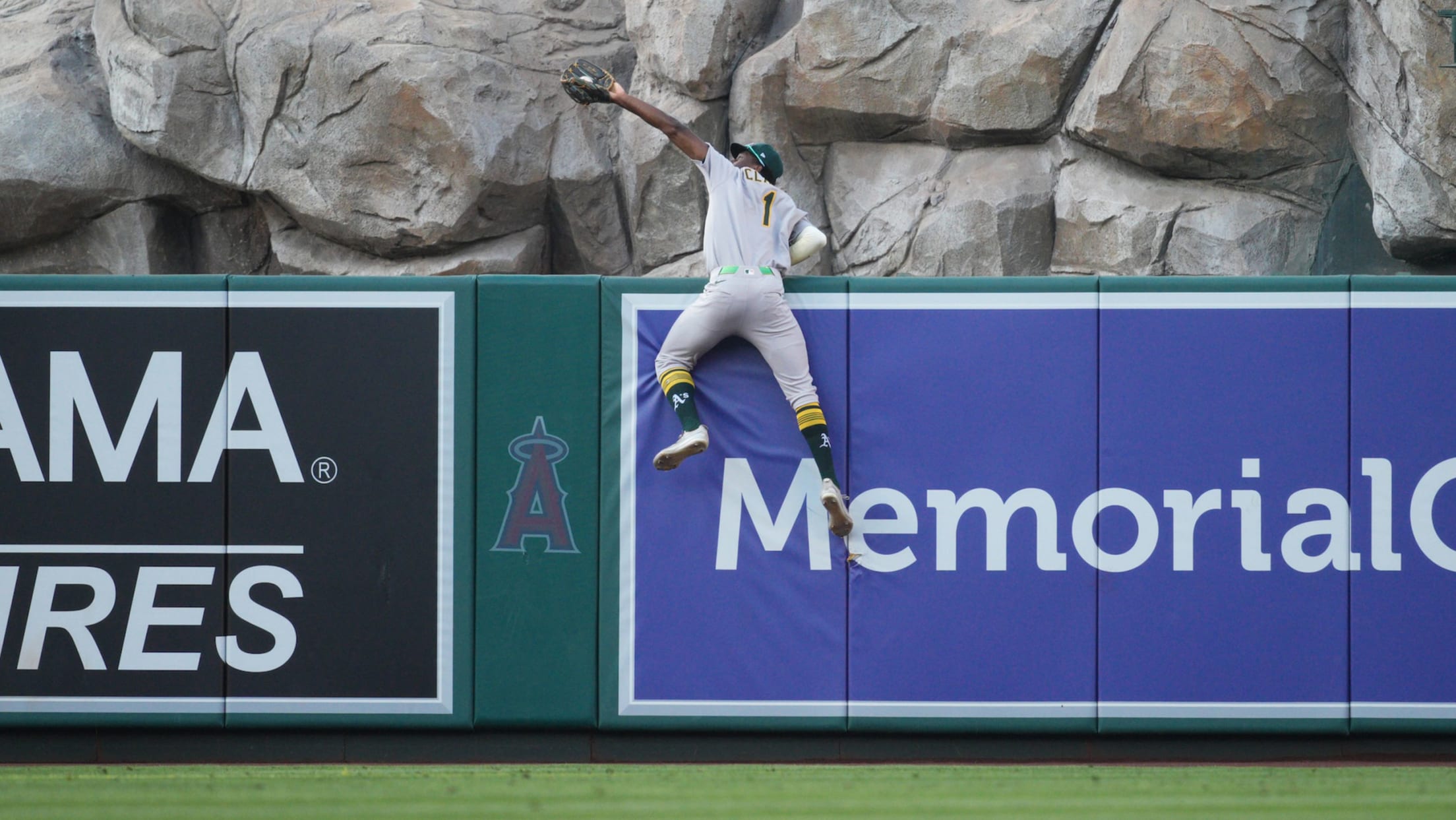 A's center fielder Denzel Clarke holds onto the wall to rob a home run