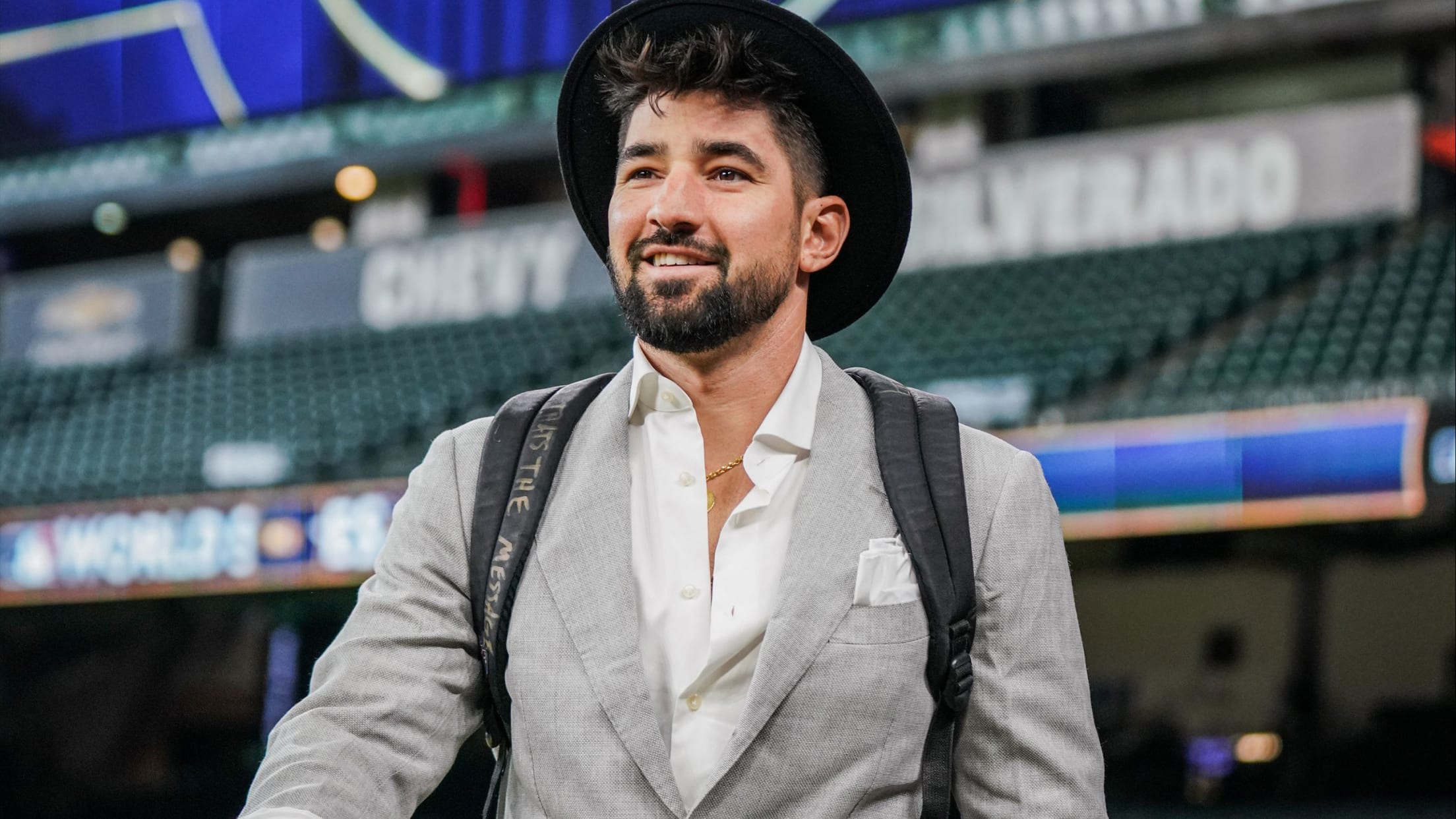 Phillies outfielder Nick Castellanos walks through the ballpark in a light-grey suit and wide-brimmed hat