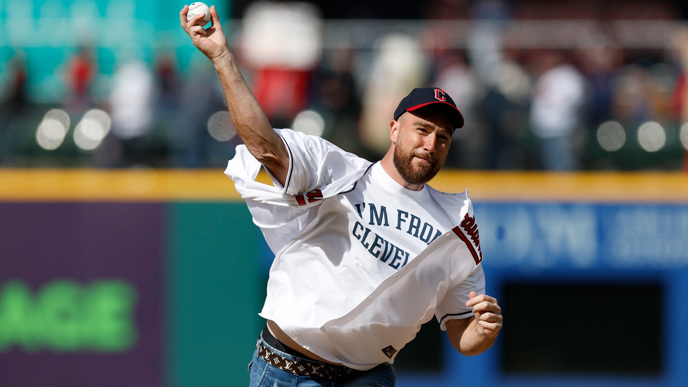 Travis Kelce throws a pitch wearing a Guardians cap and a T-shirt that says, ''I'm from Cleveland''