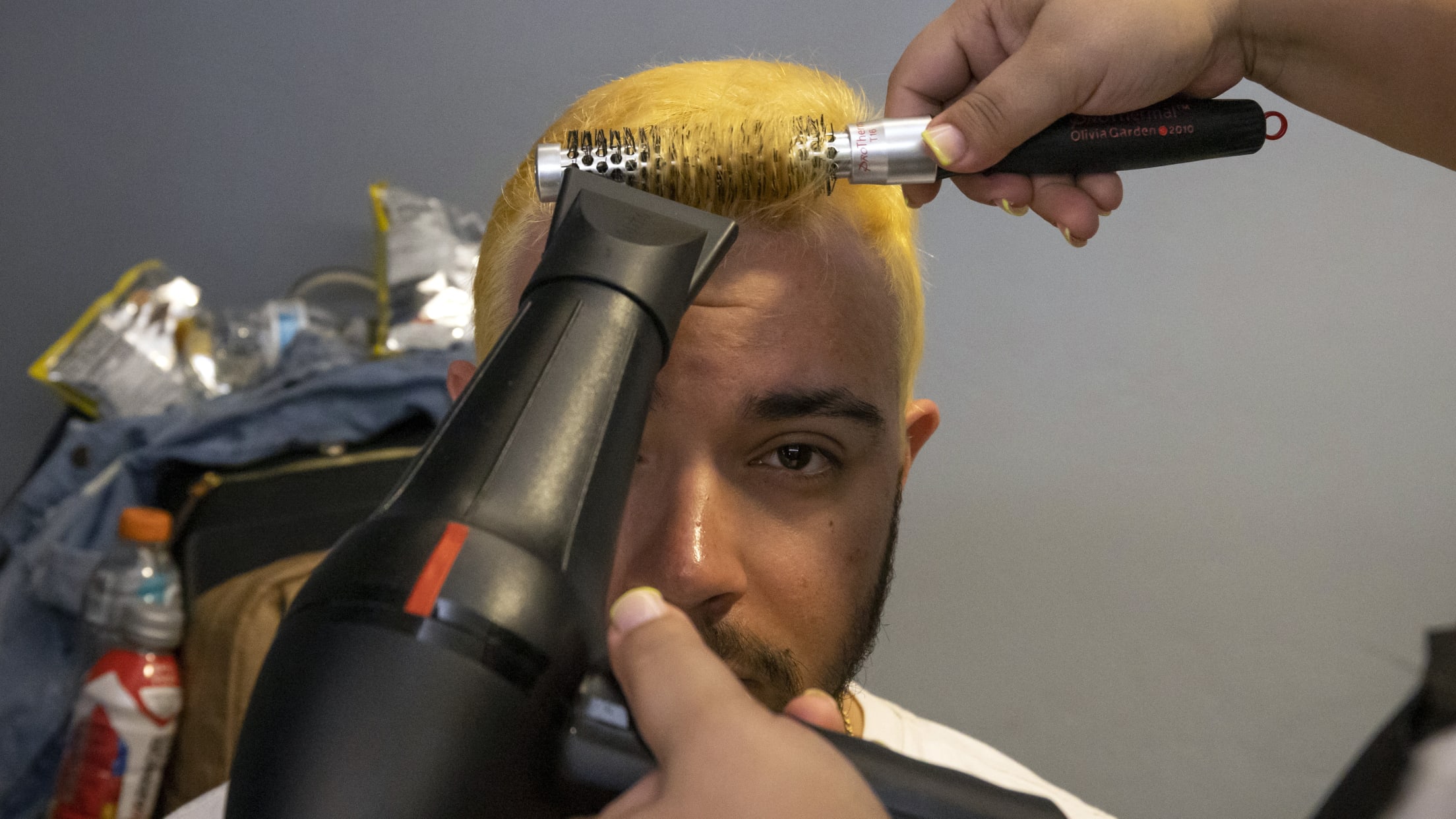 A fan has his blond hair styled with a roller and blowdryer