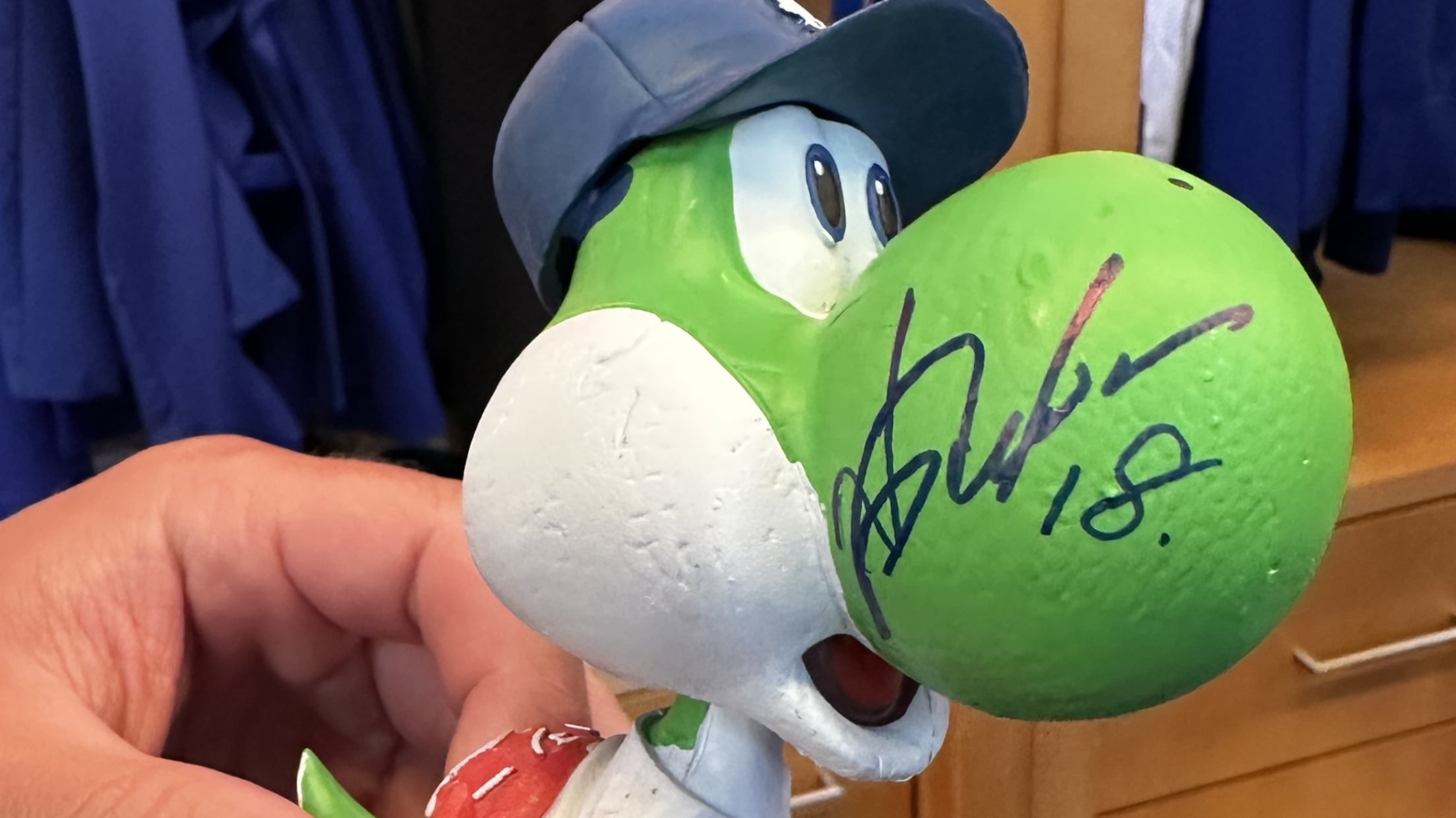 A Yoshi bobblehead with an autograph on its nose