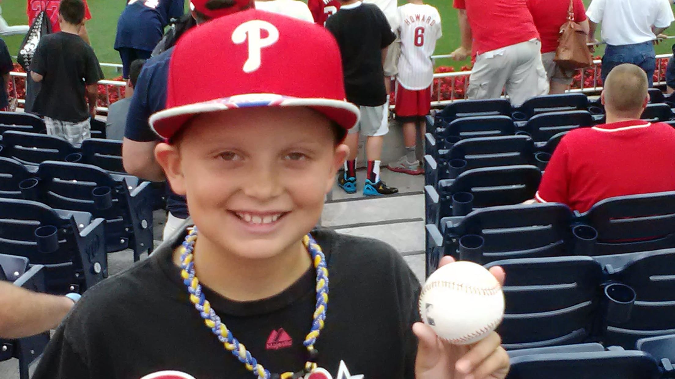 A young Nick Kurtz in a Phillies cap holds up a baseball