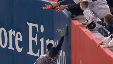 Spectator reaching over the outfield wall