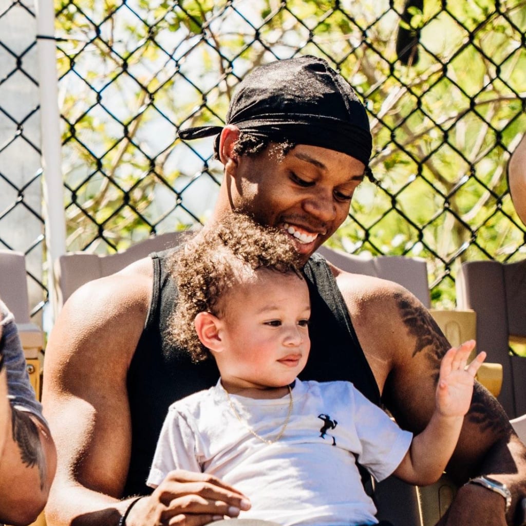 Zee Williams, Jasmine's husband, takes in a game with Baby Zee. (Photo via Jasmine Williams)