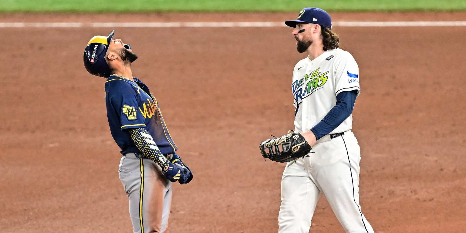 A Brewers baserunner looks skyward beside a Rays infielder during the World Series.