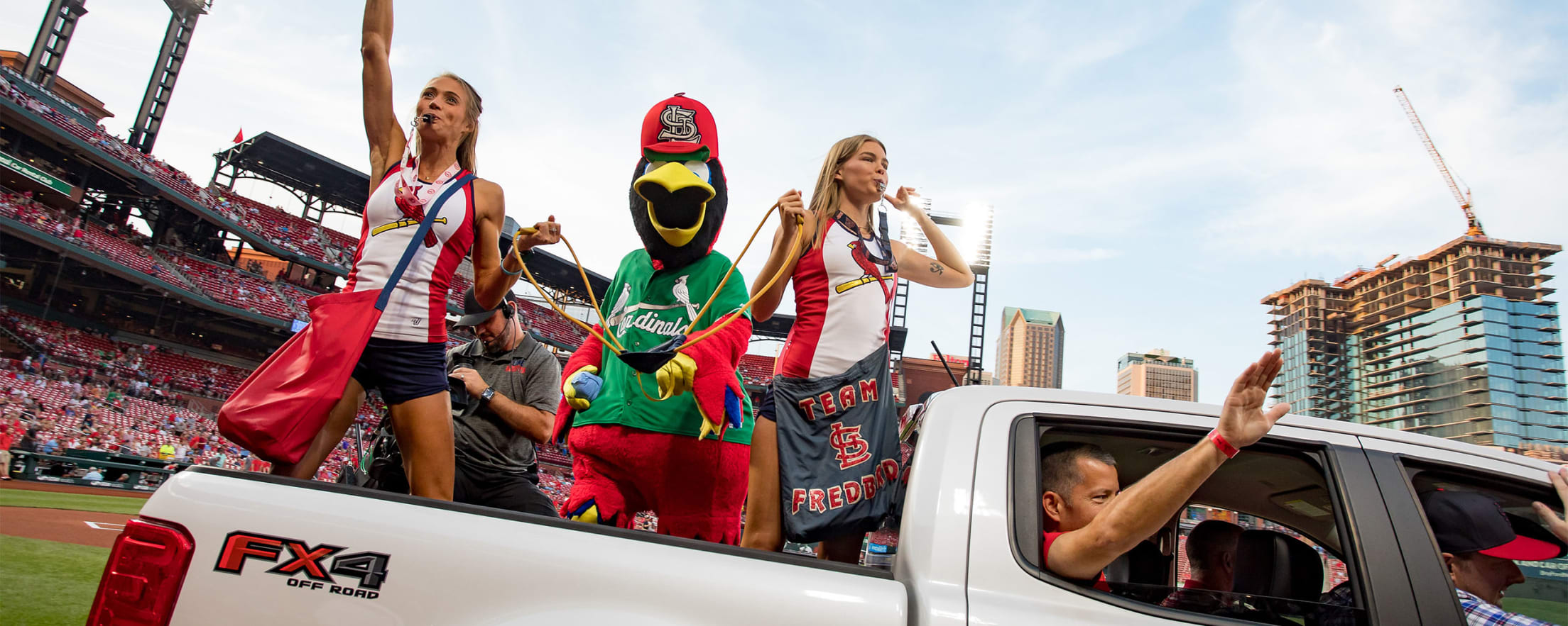 St. Louis Cardinals Fredbird girls and Fredbird the mascot launch tee shirts  into the crowd from the back of a pickup truck before the Milwaukee  Brewers-St. Louis Cardinals baseball game at Busch