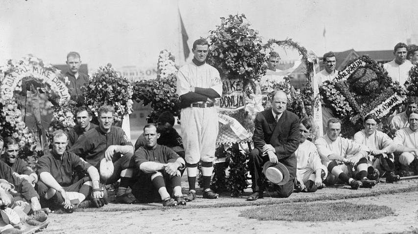 Mike Donlin (center) being celebrated by teammates and manager John McGraw, kneeling (center)